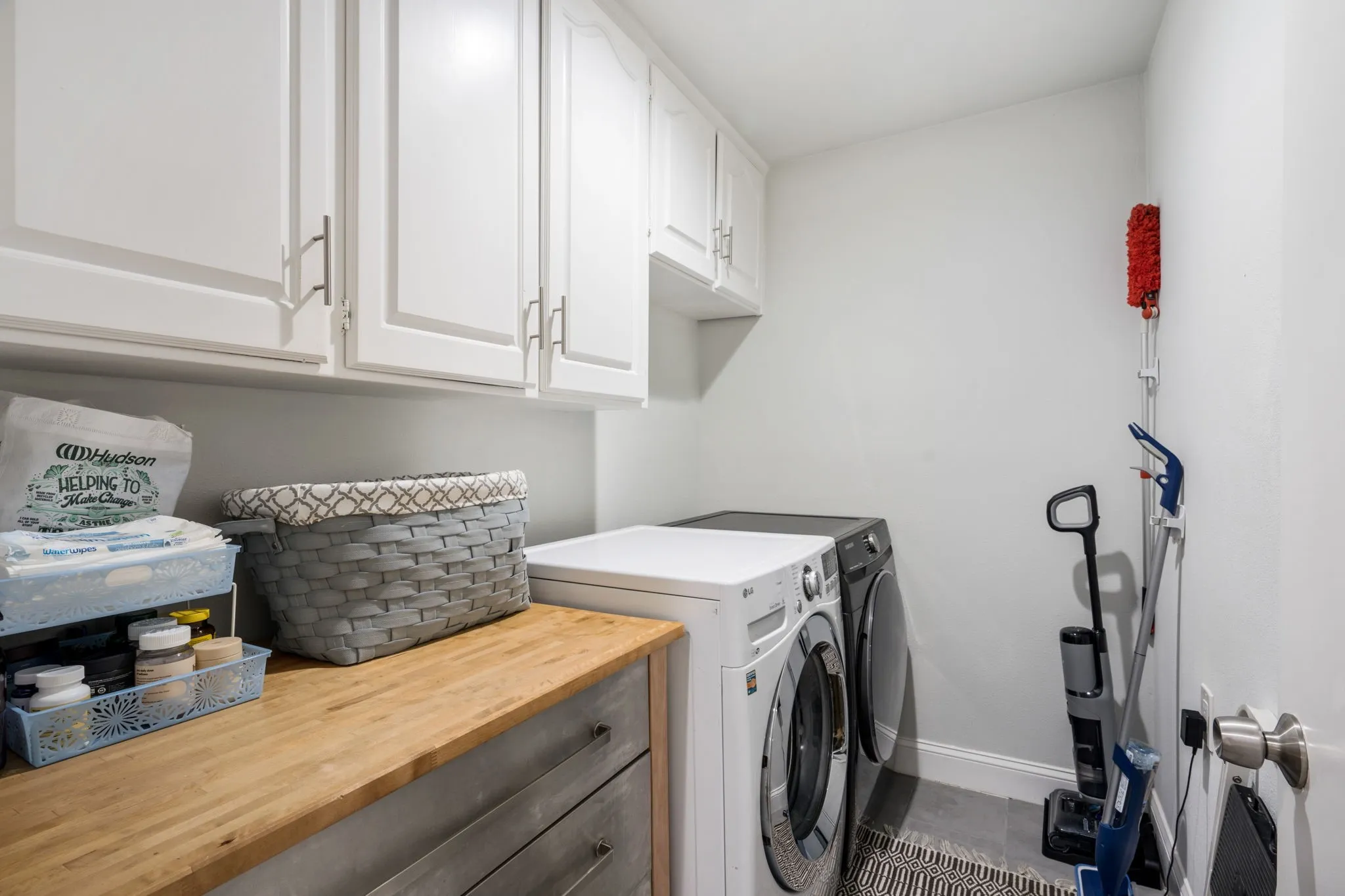 White upper cabinetry, wood-finish countertop, and gray wood-finish lower cabinetry