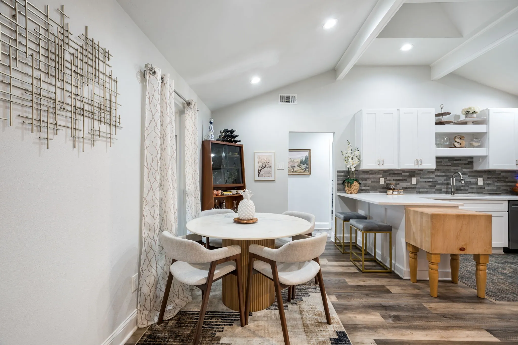 Vaulted ceilings with exposed beams, recessed lighting, wood-finish flooring, white cabinetry, and a subway tile backsplash