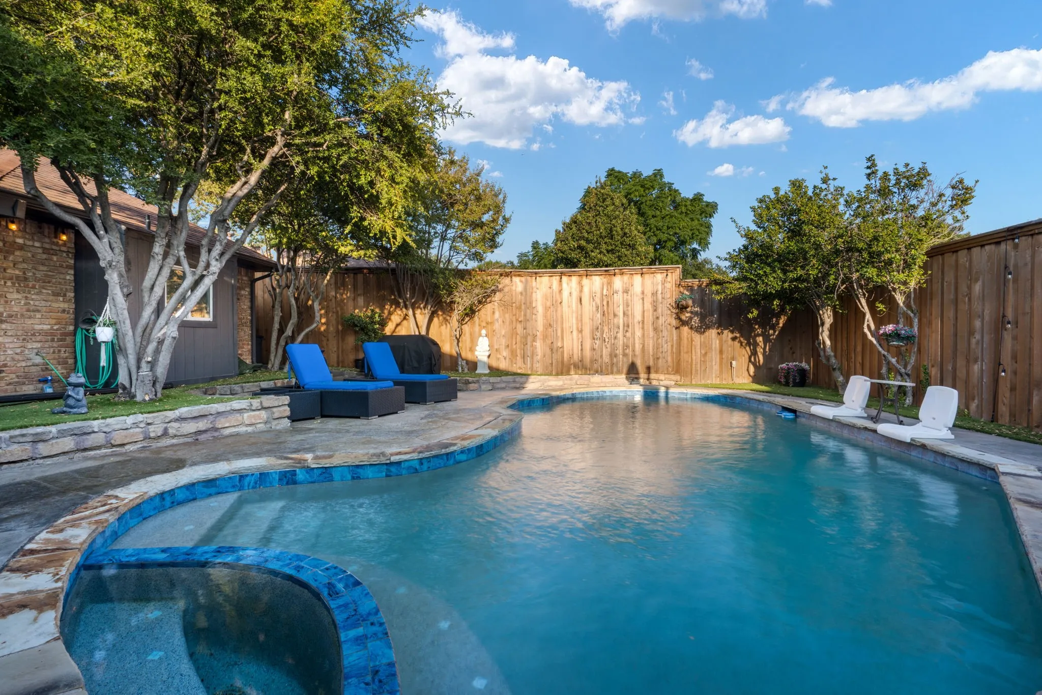 Swimming pool with integrated spa, stone coping, and a tiled waterline