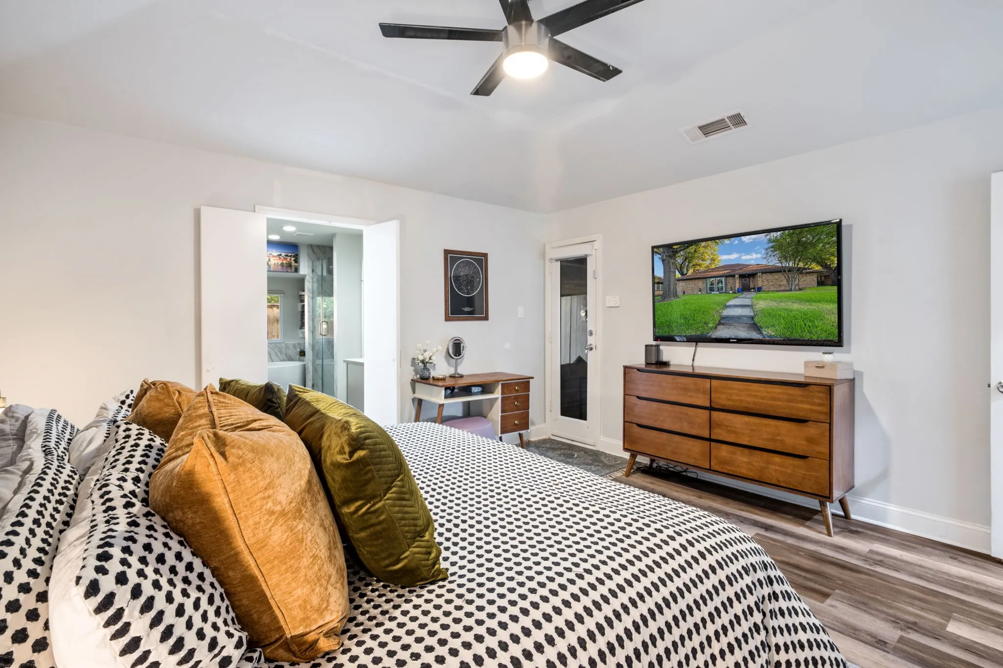 Vaulted ceiling with a ceiling fan, double-door entry, exterior access door, and wood-finish flooring