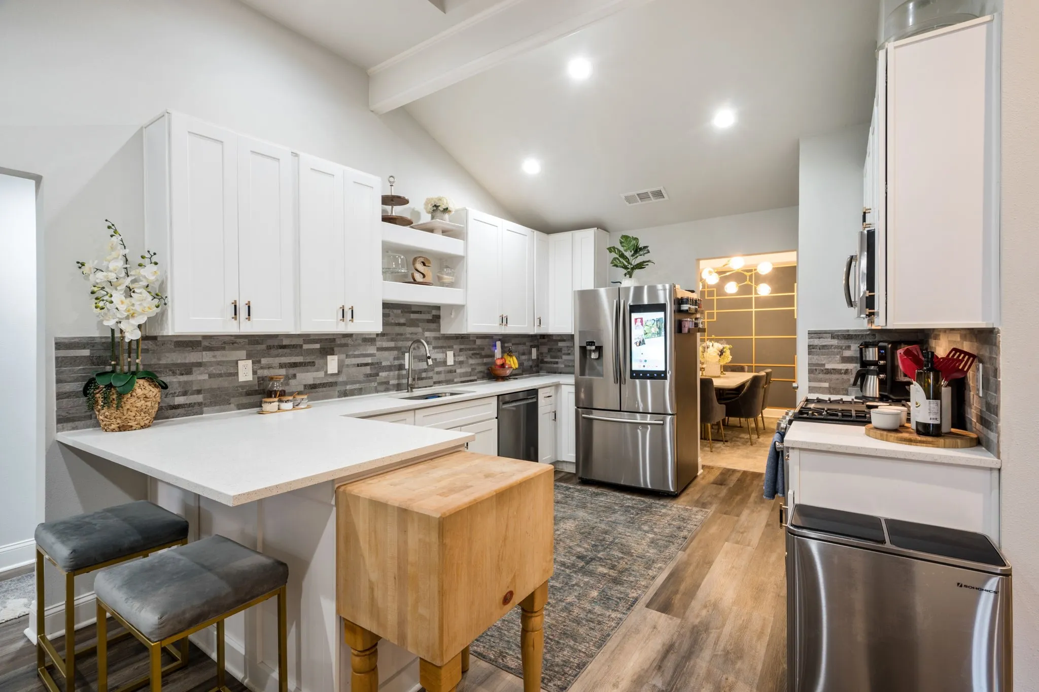 Kitchen featuring white shaker cabinetry, stainless steel appliances, mosaic tile backsplash, wood-finish flooring, and recessed lighting