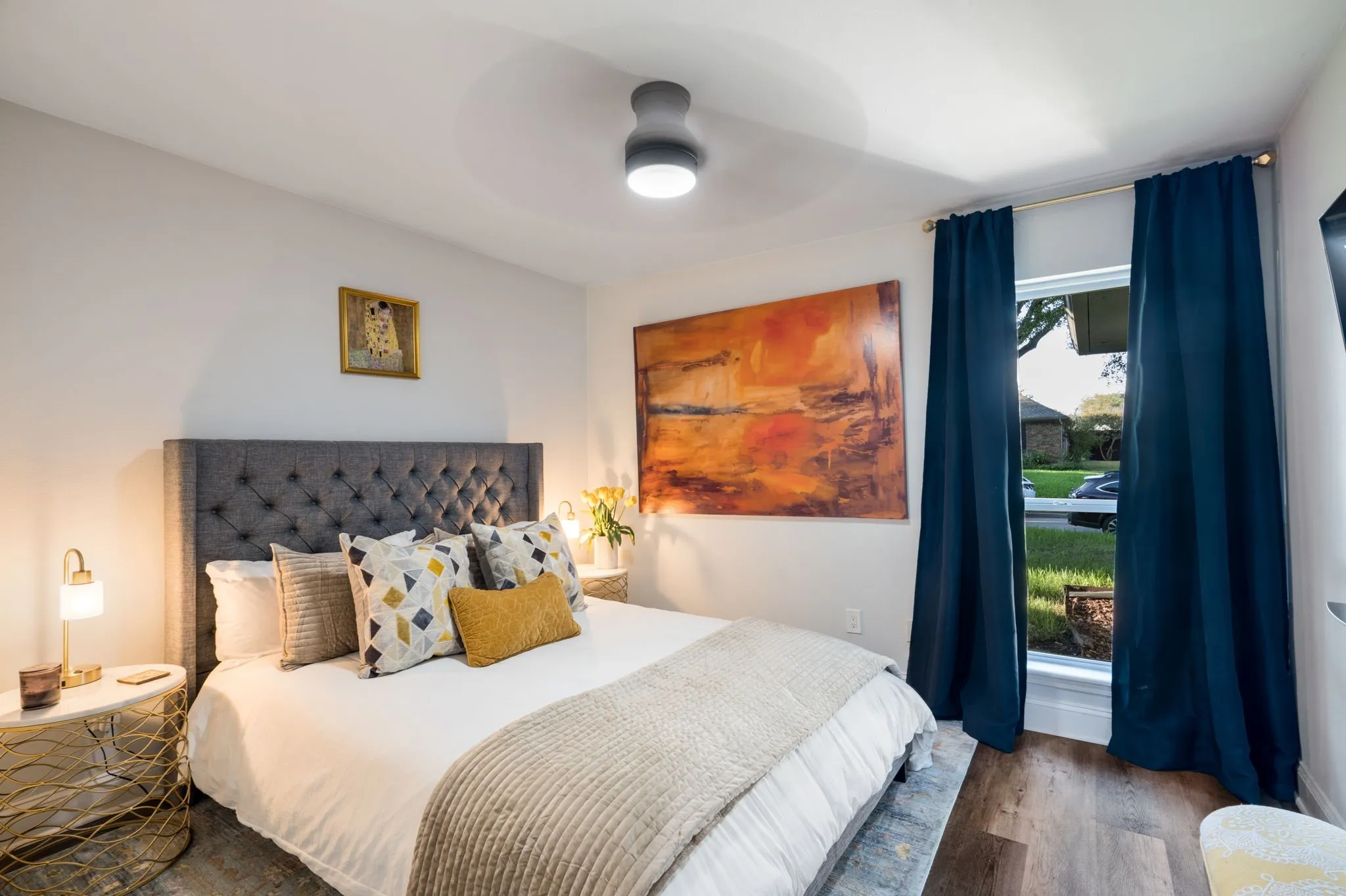wood-finish flooring, a contemporary ceiling fan, and a single window with white trim