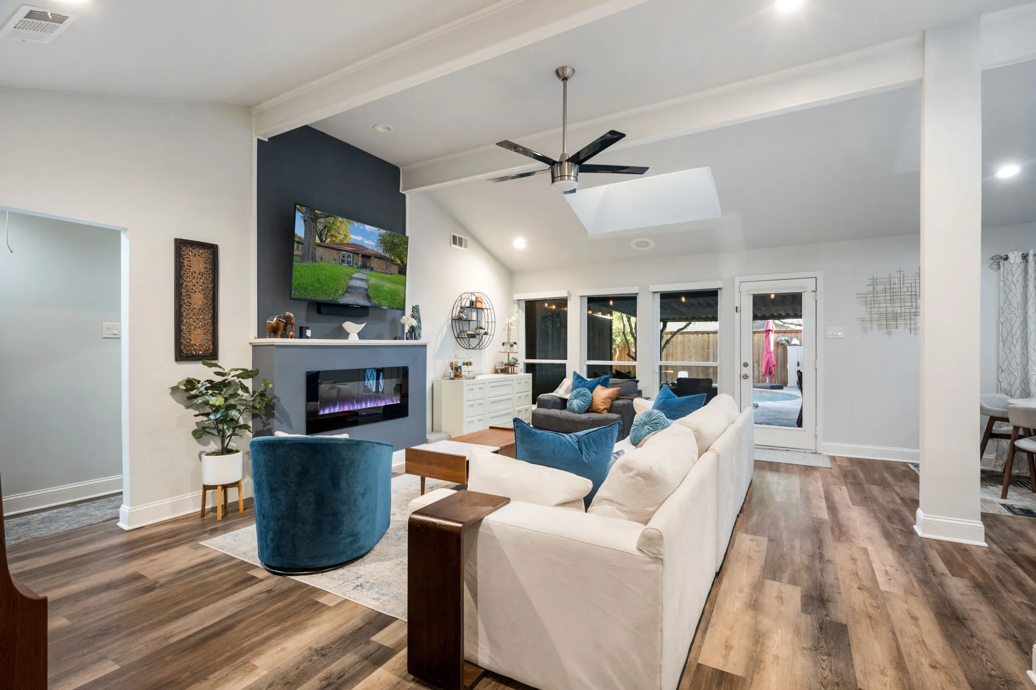 Wood-finish flooring throughout, vaulted ceiling with exposed beams, built-in electric fireplace, recessed lighting, and a skylight
