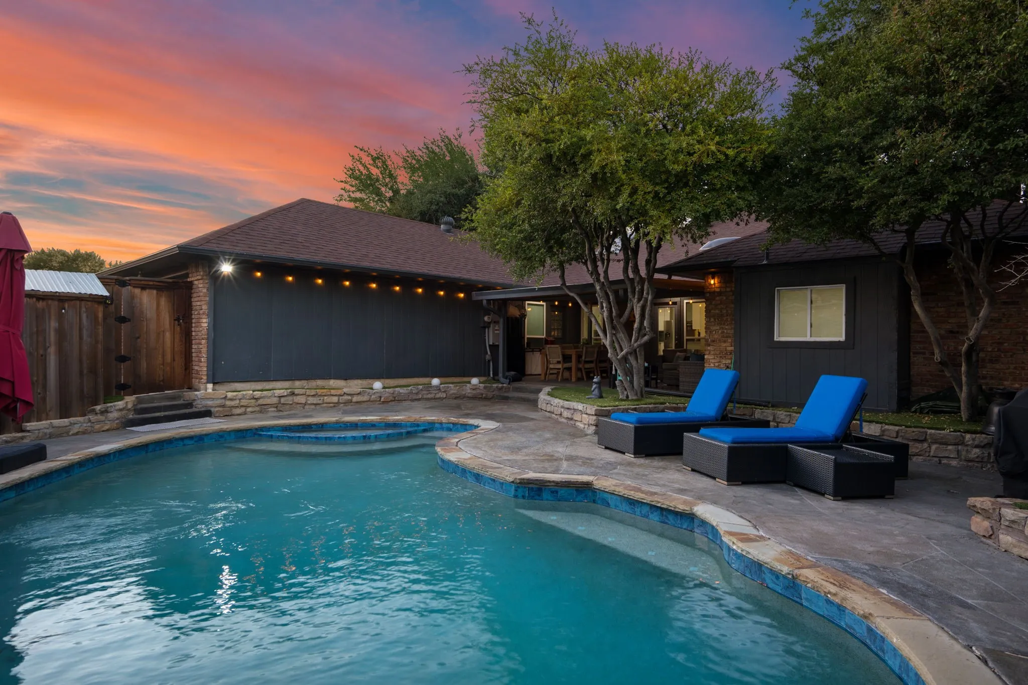 backyard oasis with pool lounge seating, spa, string lights and covered patio