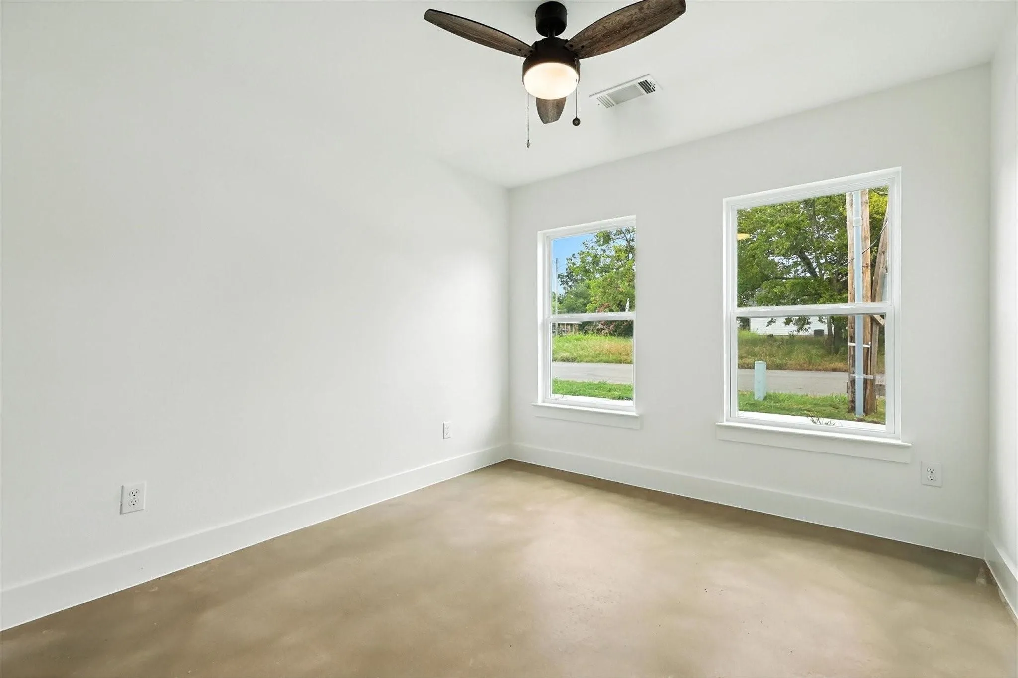 Smooth concrete flooring, dual pane windows, a ceiling fan with integrated lighting, and crisp white wall finishes
