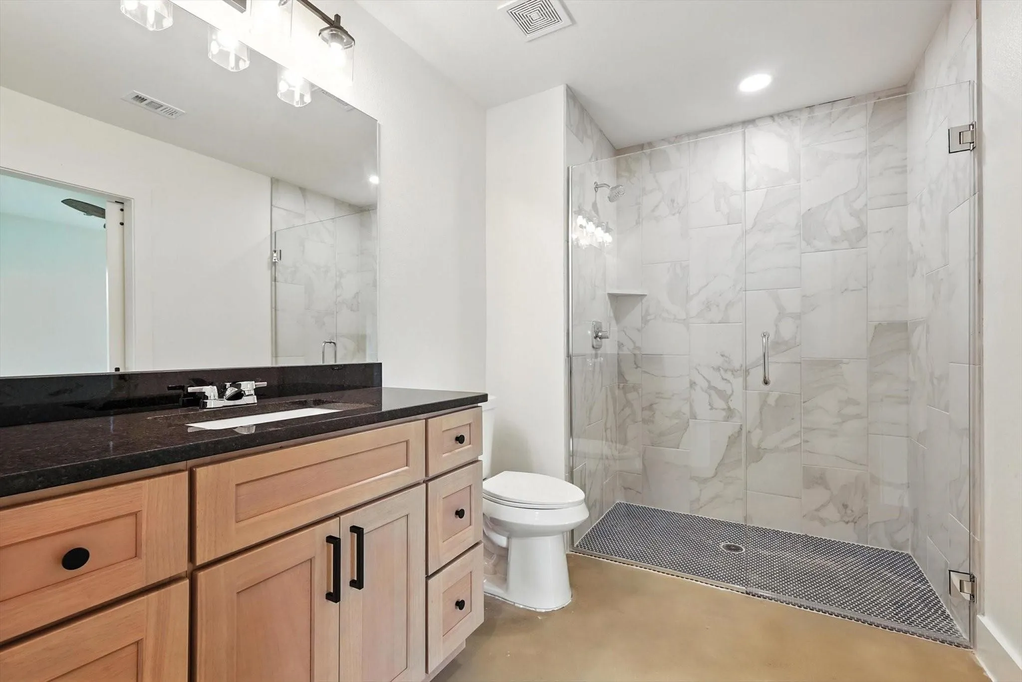 Wood-finish vanity with dark countertop, undermount sink, and integrated mirror