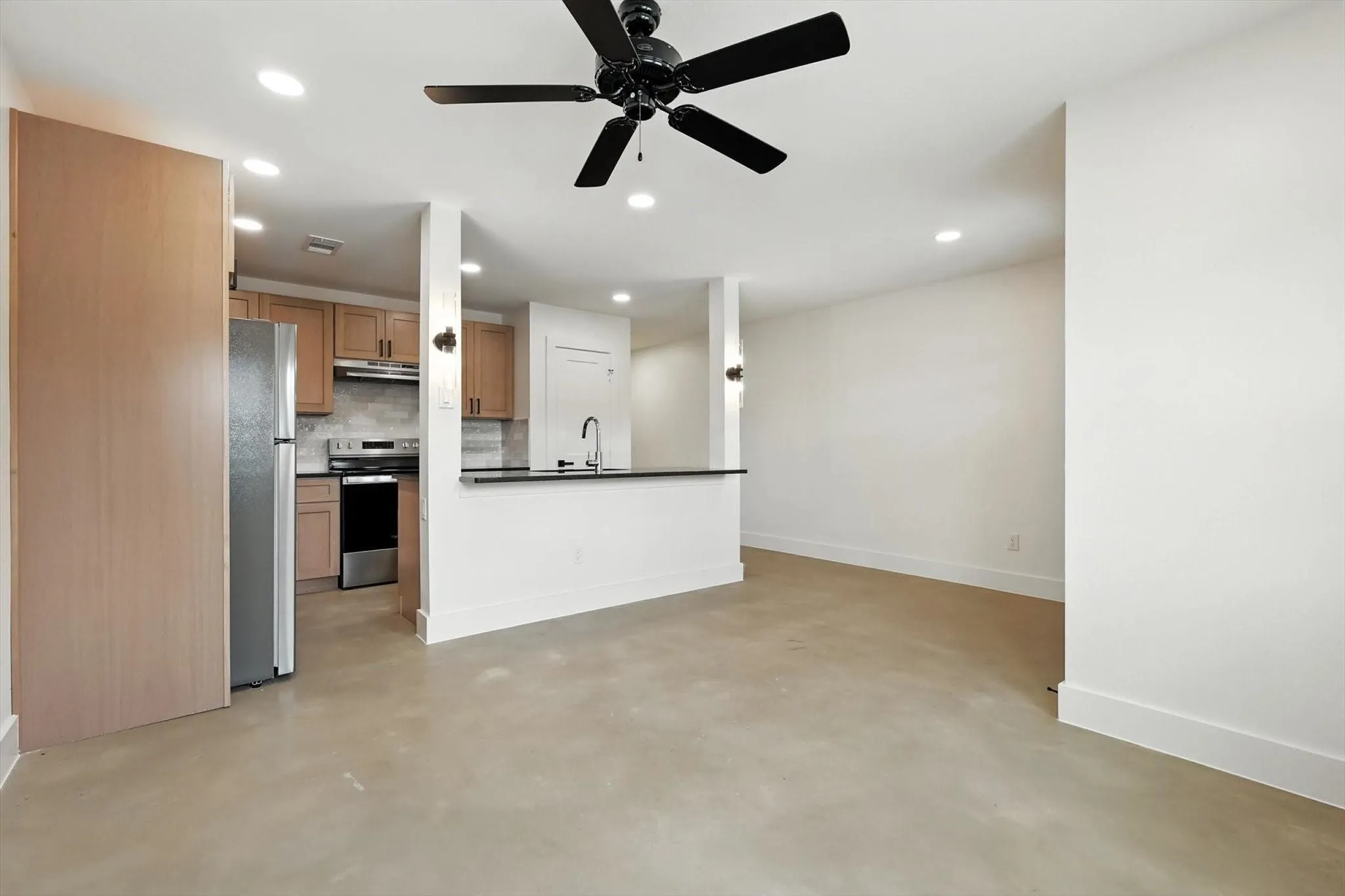 Open-concept living space with concrete flooring, recessed lighting, and a black ceiling fan