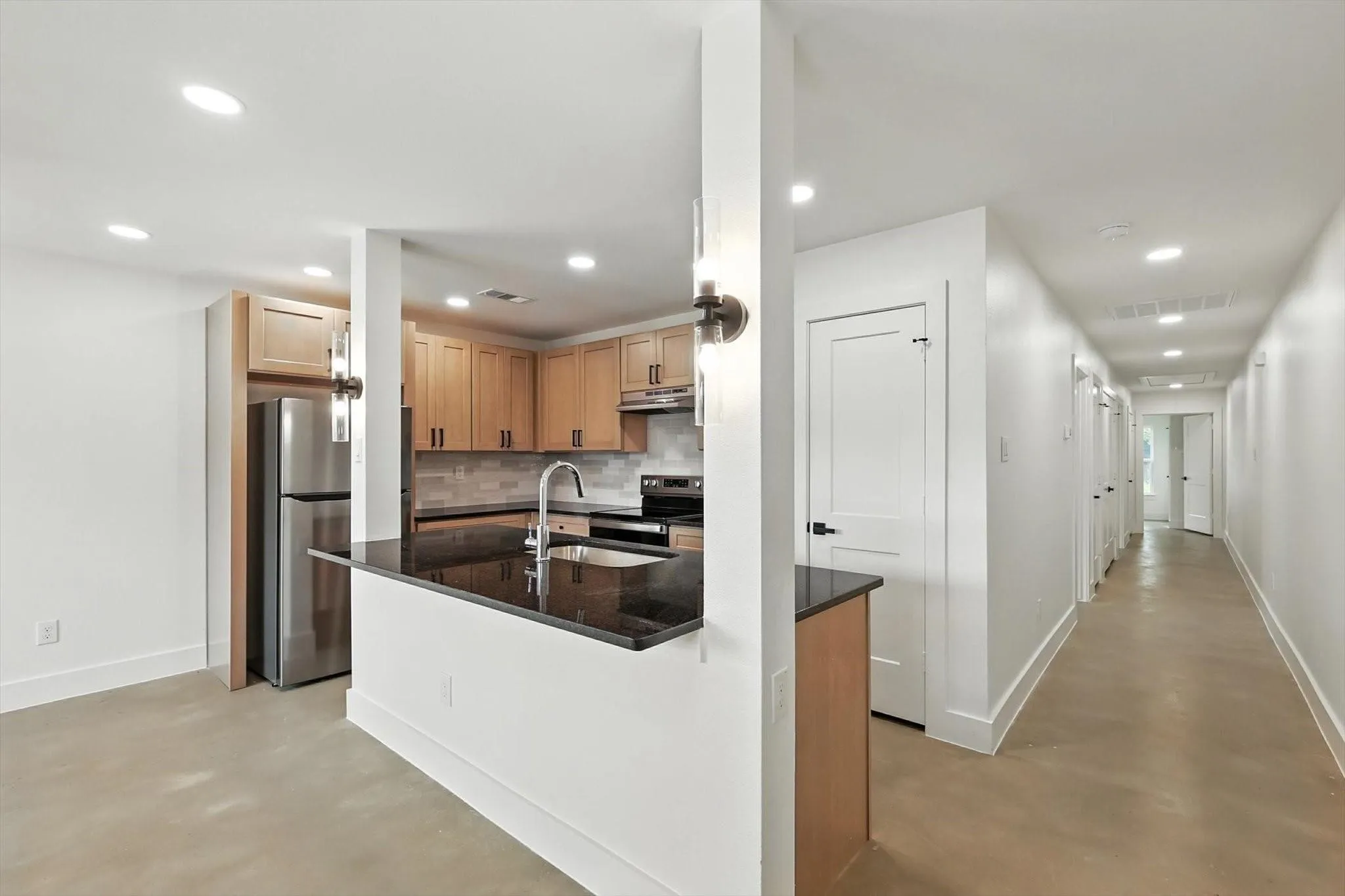 Kitchen featuring wood cabinetry, stainless steel appliances, dark countertops, and a tile backsplash
