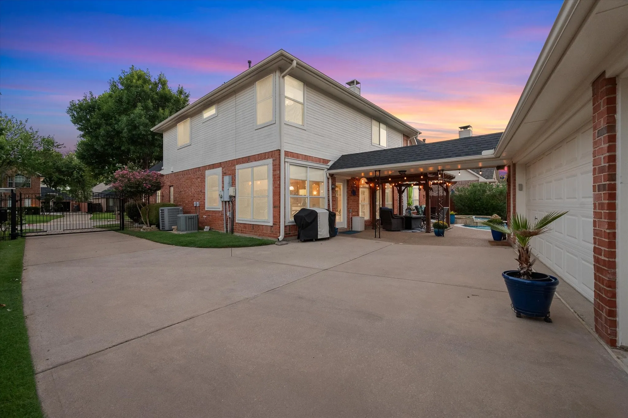 Expansive concrete driveway with a wrought iron gate. 3-car garage