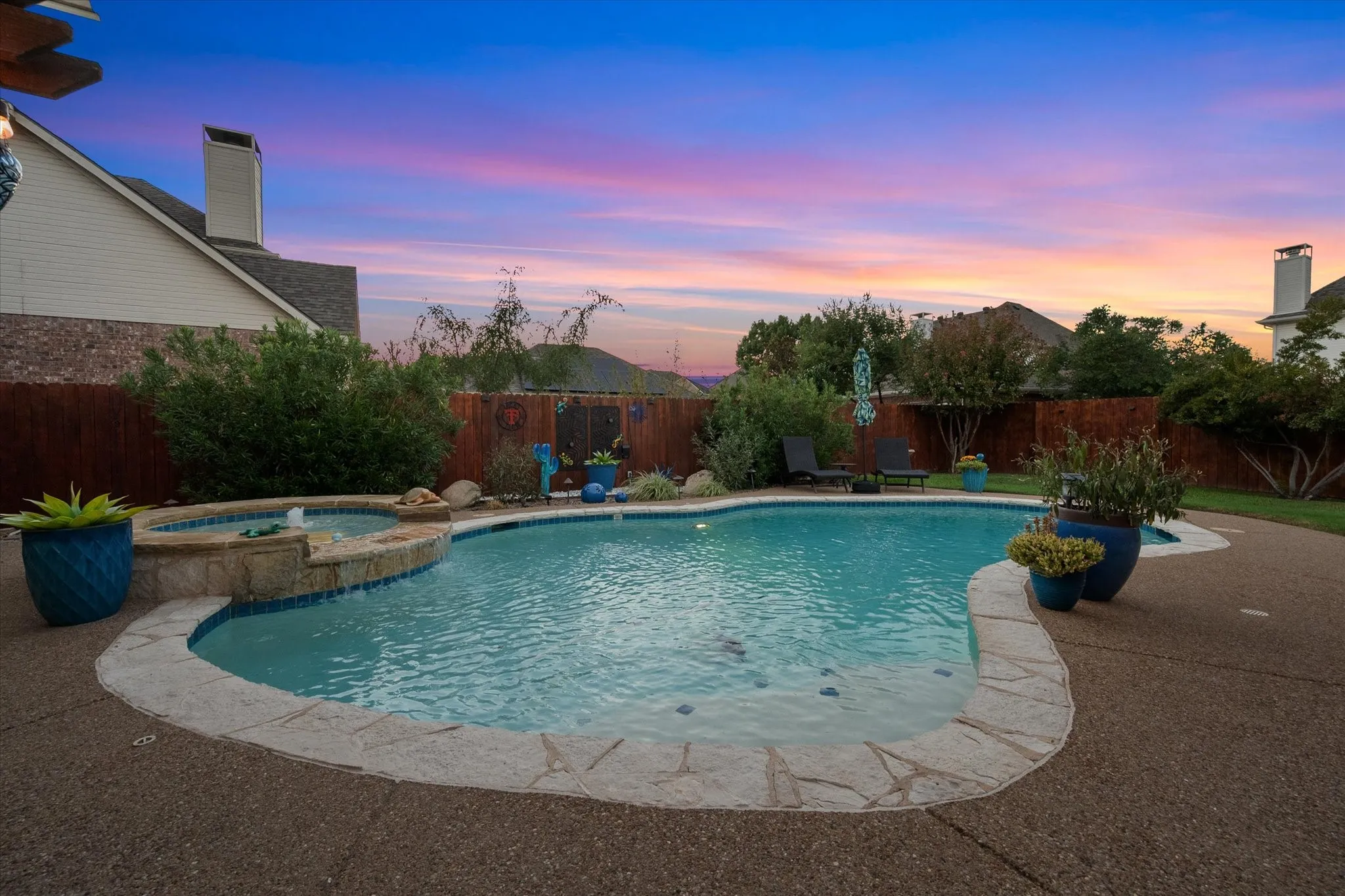 Freeform swimming pool with integrated spa and stone coping
