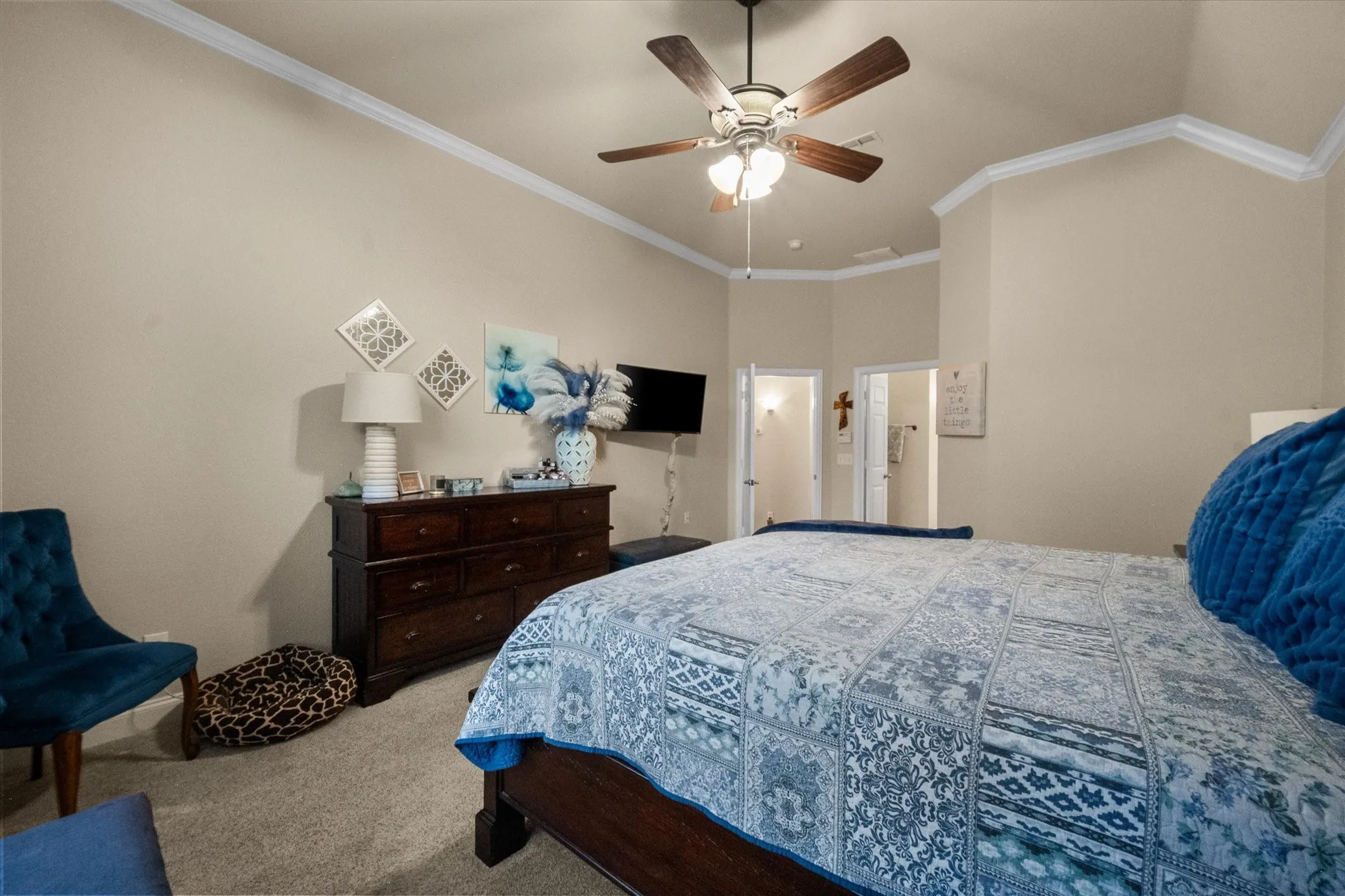 Vaulted ceiling with crown molding, ceiling fan with integrated lighting, and carpeted flooring