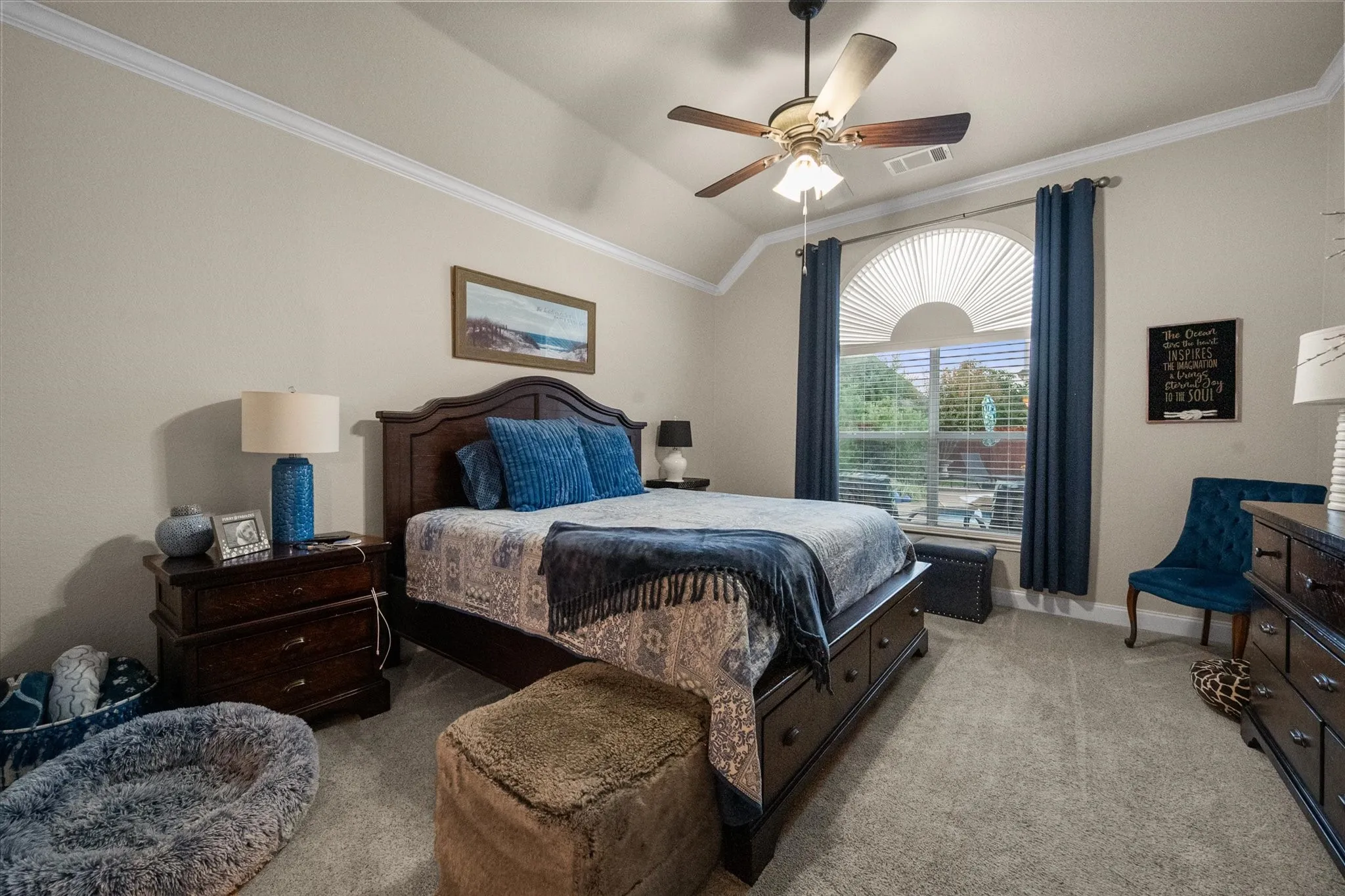 Vaulted ceiling with crown molding, ceiling fan, arched window, and carpet flooring