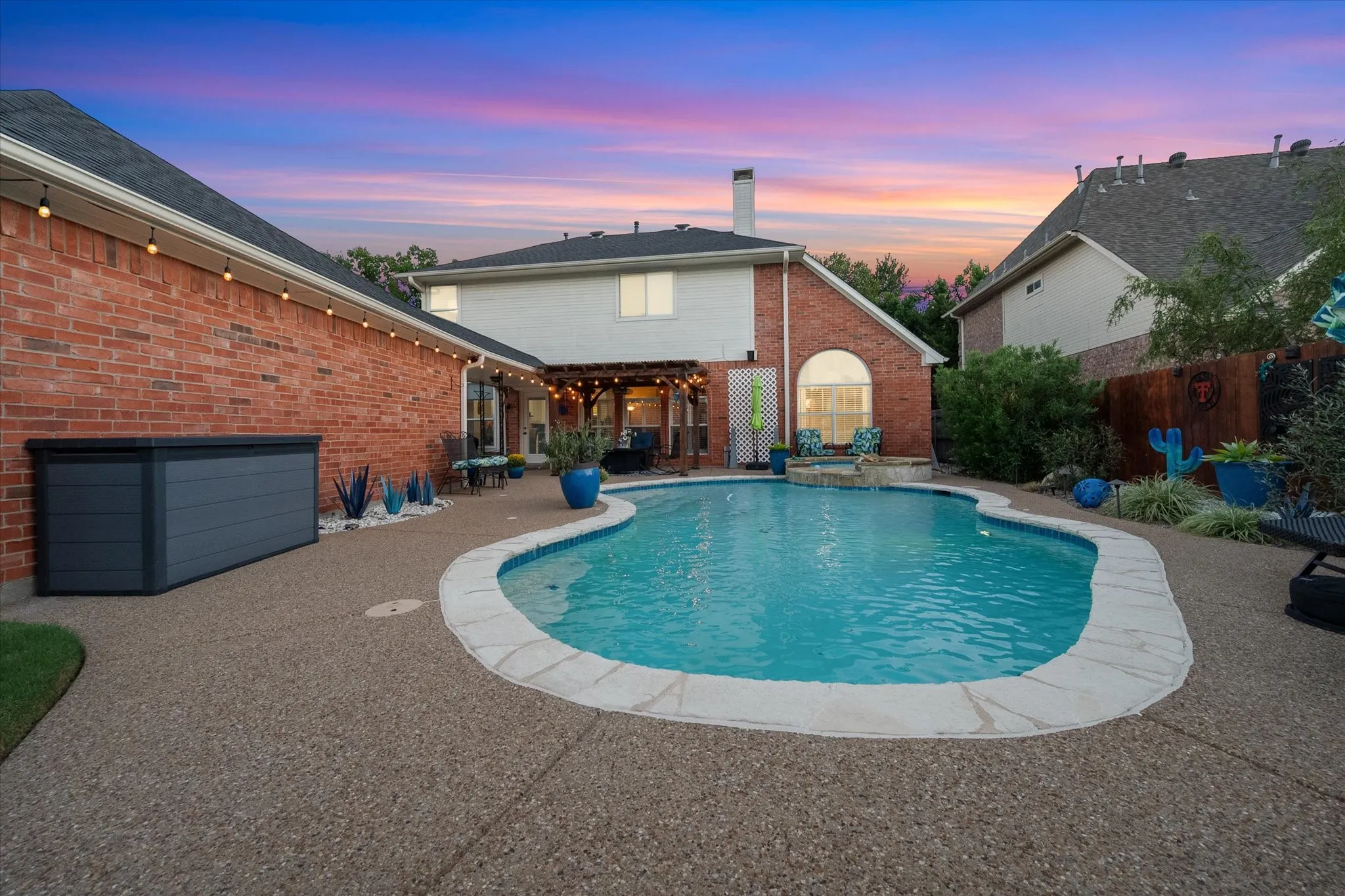 Backyard oasis featuring an in-ground swimming pool, expansive hardscaping, and a covered patio with a pergola