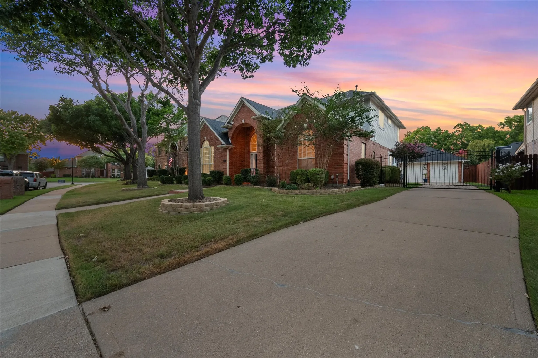 Brick exterior, arched entryway, established landscaping, concrete driveway, and detached 3-car garage structure