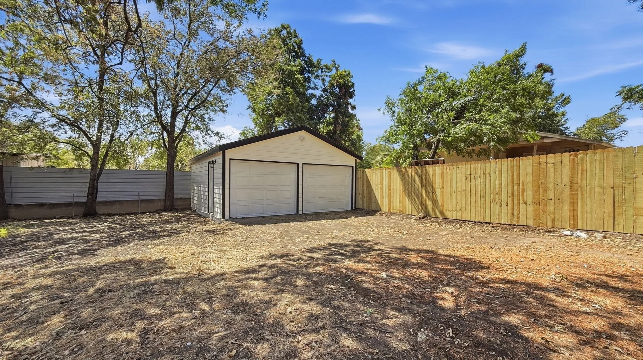 Detached two-car garage with white paneled doors and a side access door