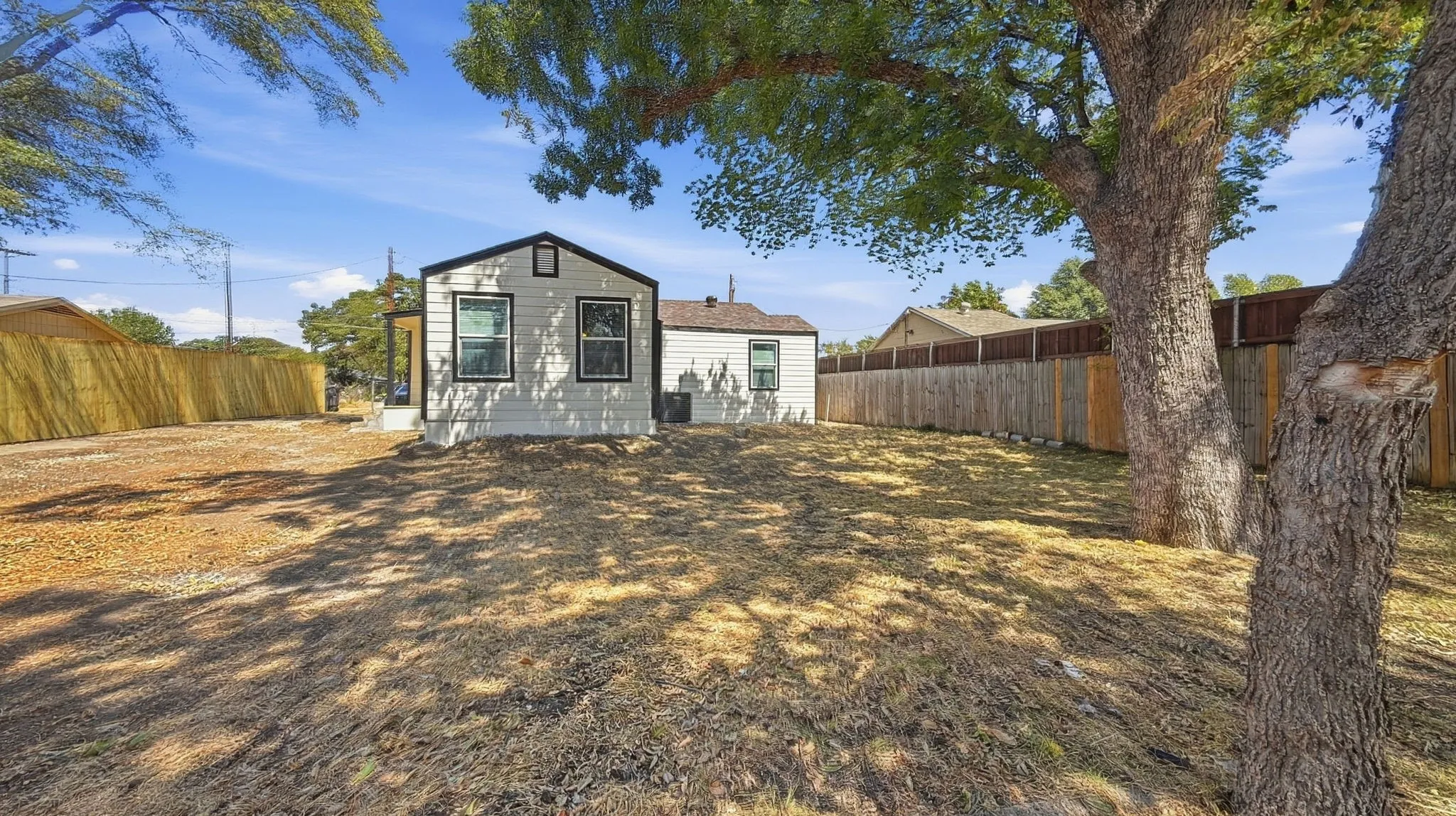 Expansive yard featuring mature trees and a wooden privacy fence