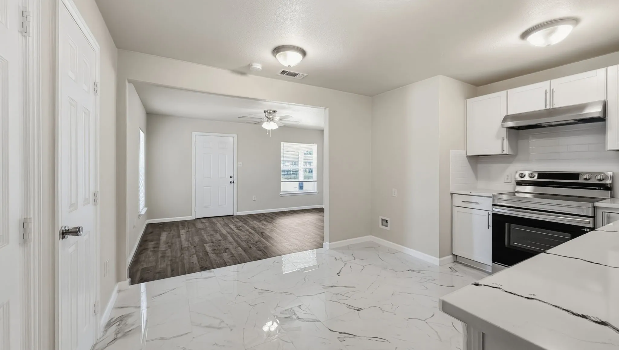 Marble-finish flooring, white cabinetry, stainless steel range, and wood-finish flooring