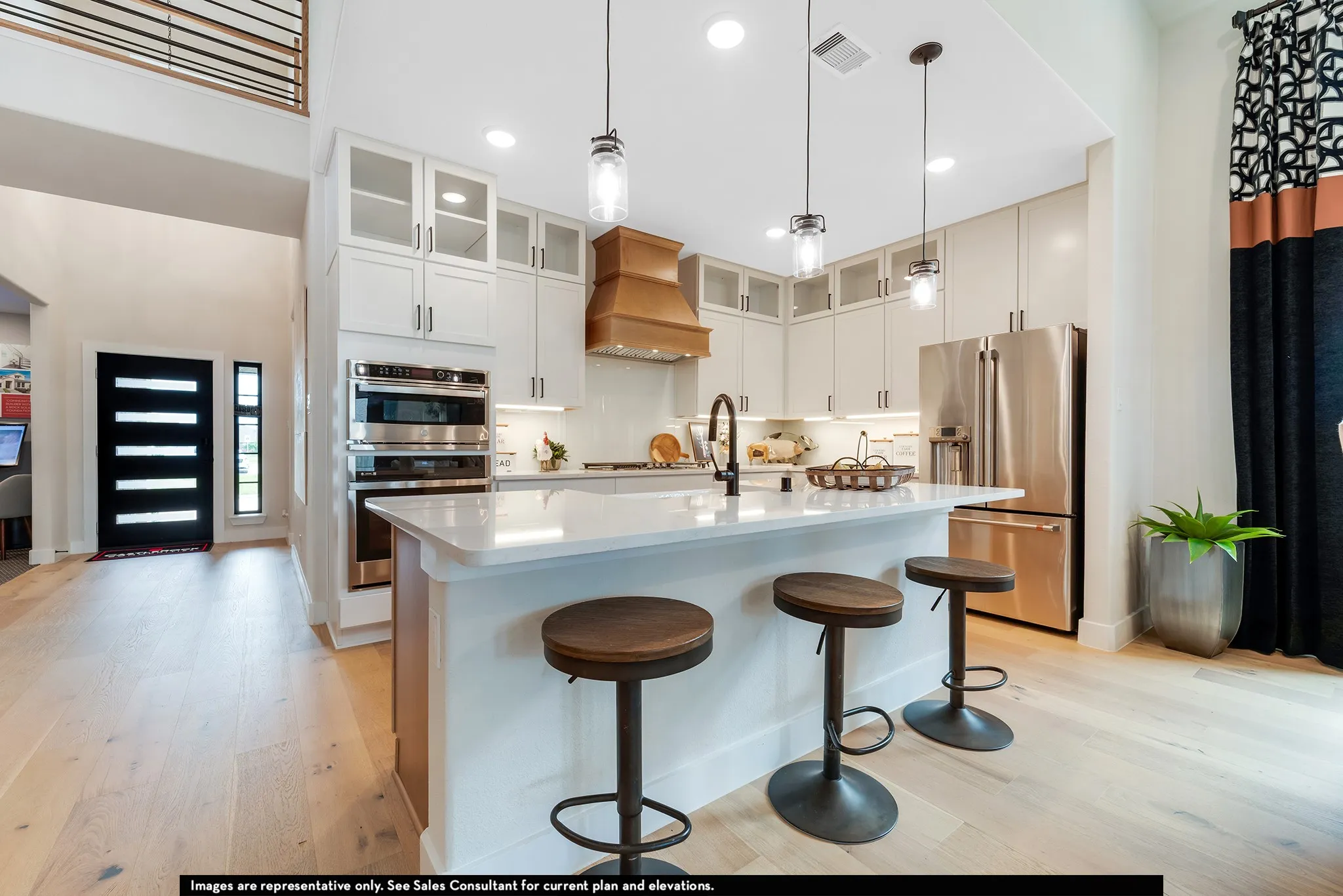 Gourmet kitchen with a large central island, white cabinetry, stainless steel appliances, and wood-finish flooring