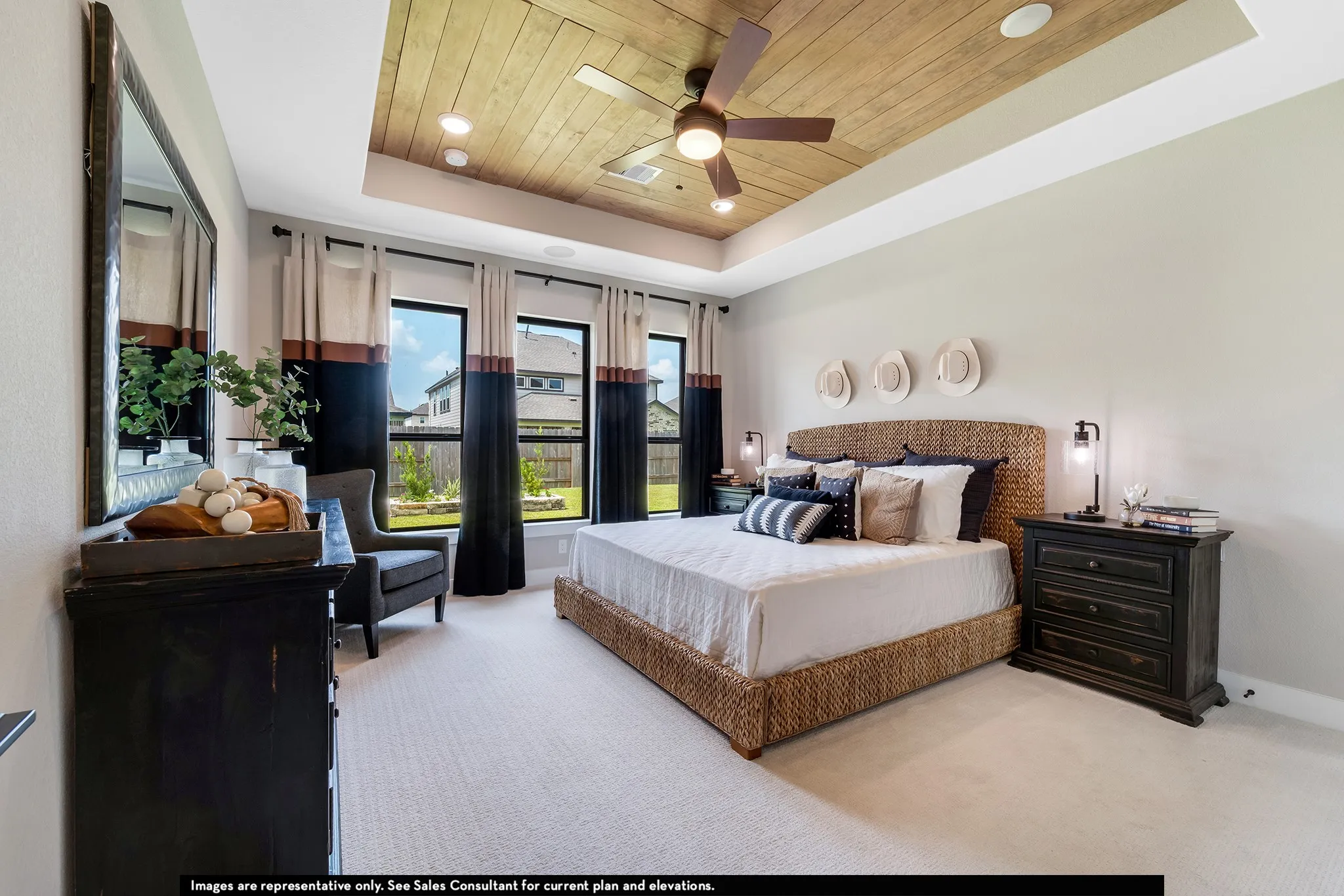 Recessed ceiling with wood-finish paneling and ceiling fan, three windows with dark frames, light-colored walls, and light carpeting