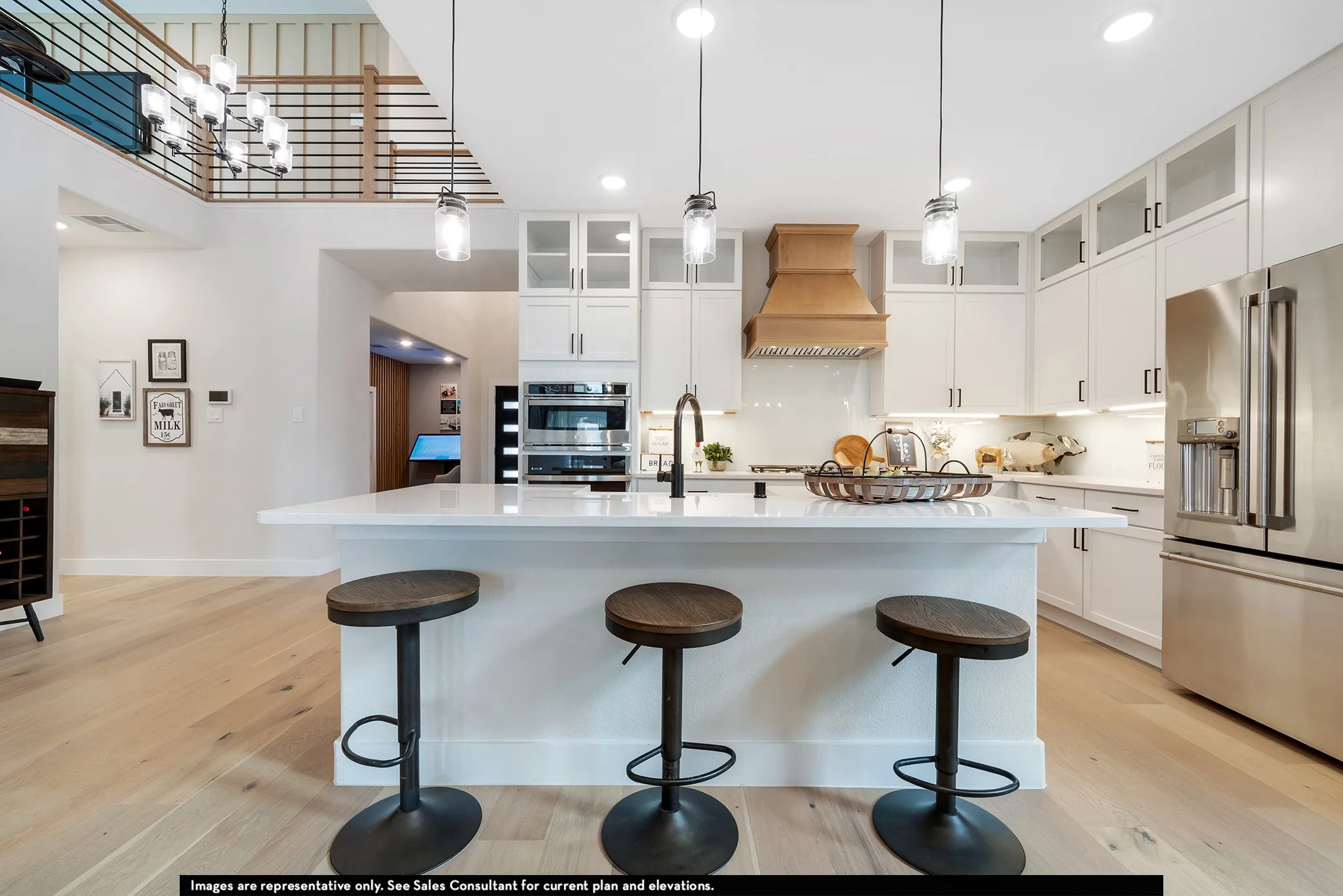 Gourmet kitchen with a large central island, white cabinetry, integrated stainless steel appliances, and wood-finish flooring