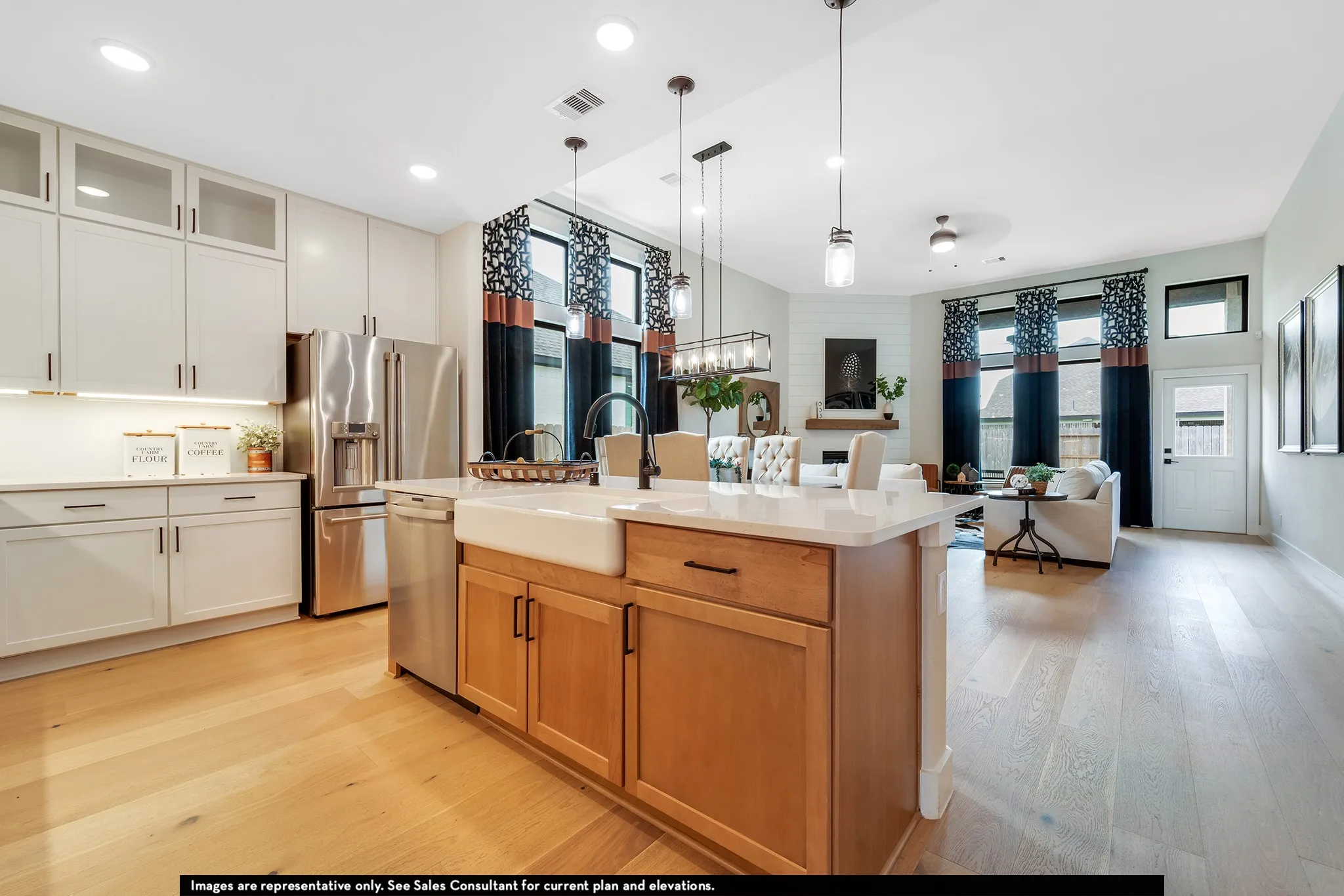 Expansive kitchen island with a farmhouse sink and light-toned wood cabinetry