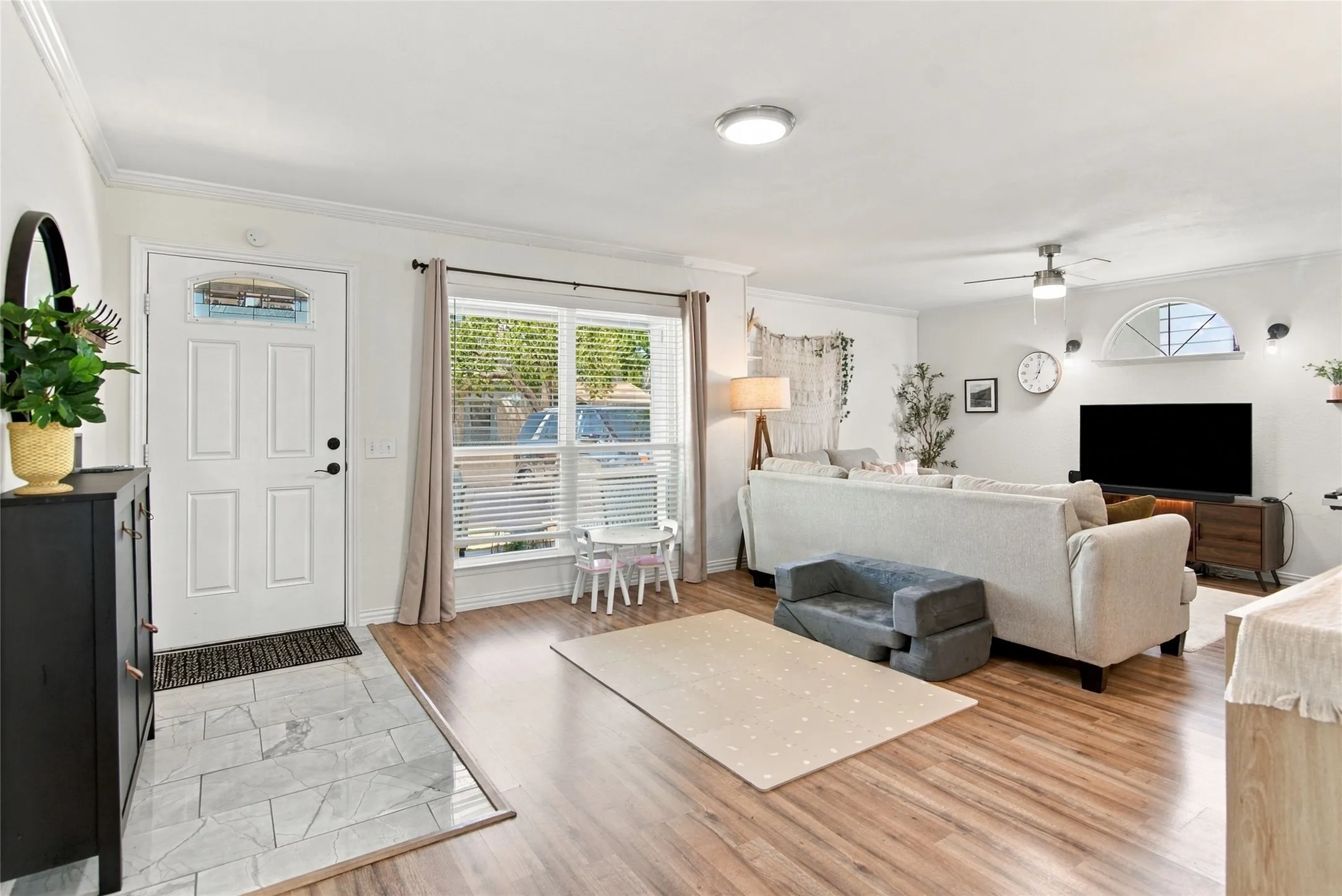 Entryway with tile flooring, wood-finish flooring, a front door with decorative glass, and a large window with blinds
