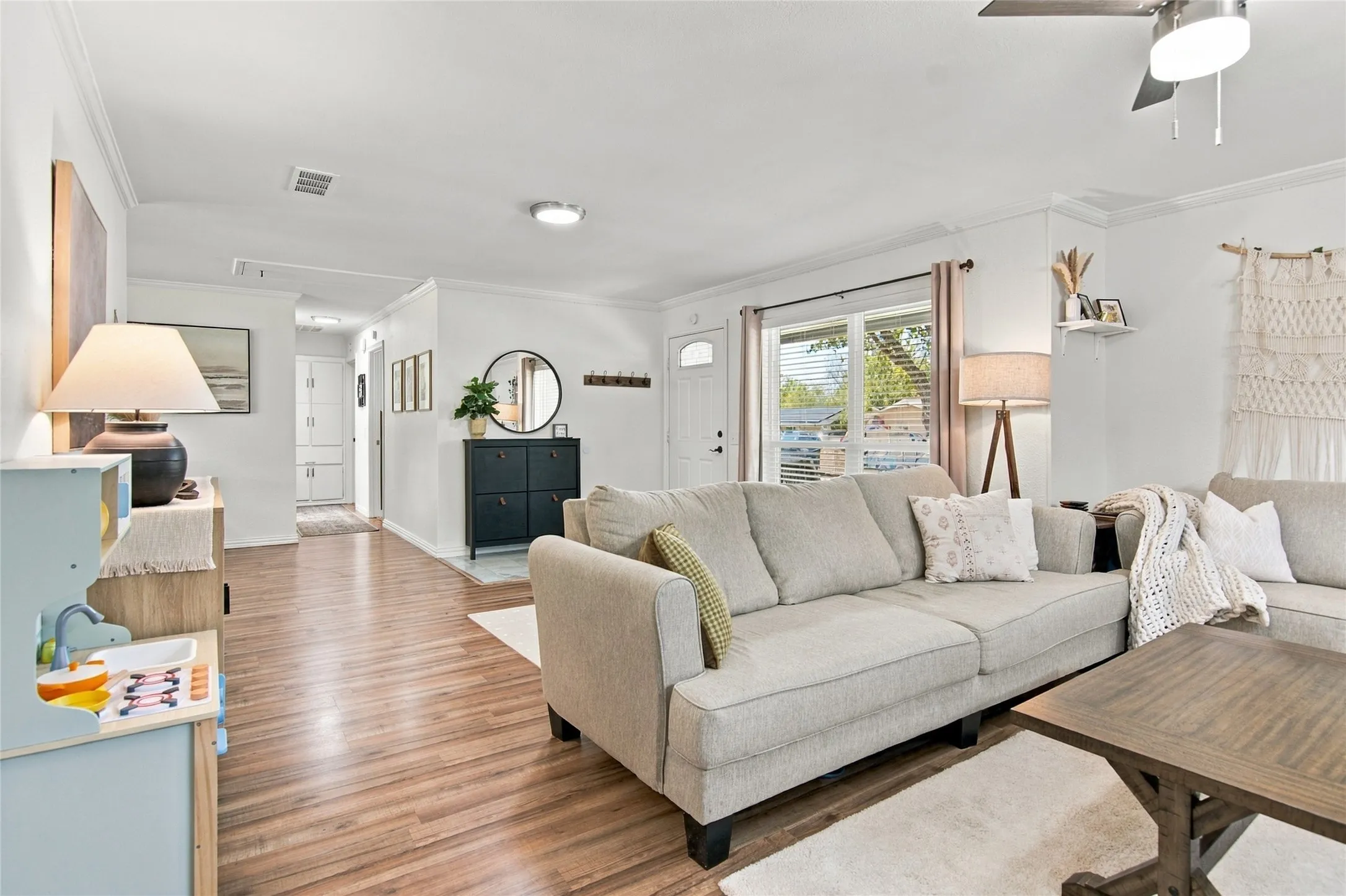 Wood-finish flooring, white walls, crown molding, and a ceiling fan with integrated lighting
