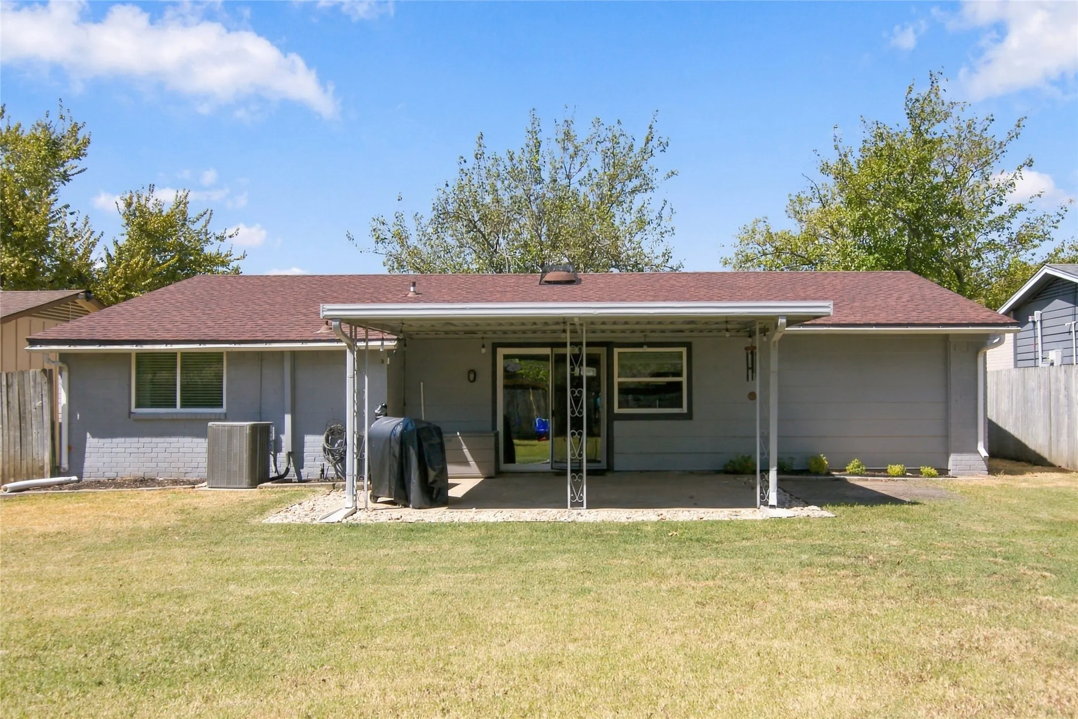 Expansive backyard featuring a covered patio, sliding glass door access, and a durable shingle roof