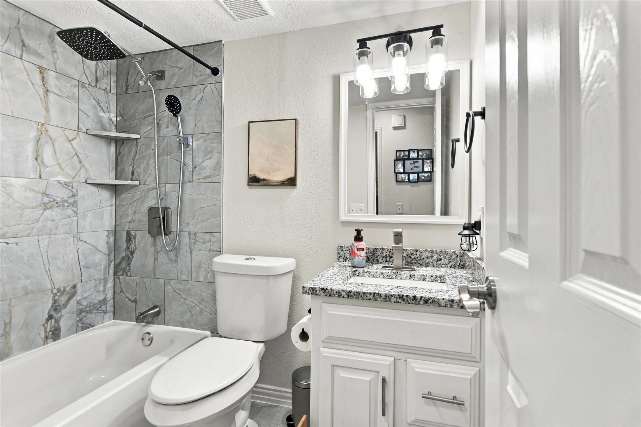 Shower/tub combination with gray stone-look tile surround and built-in shelving