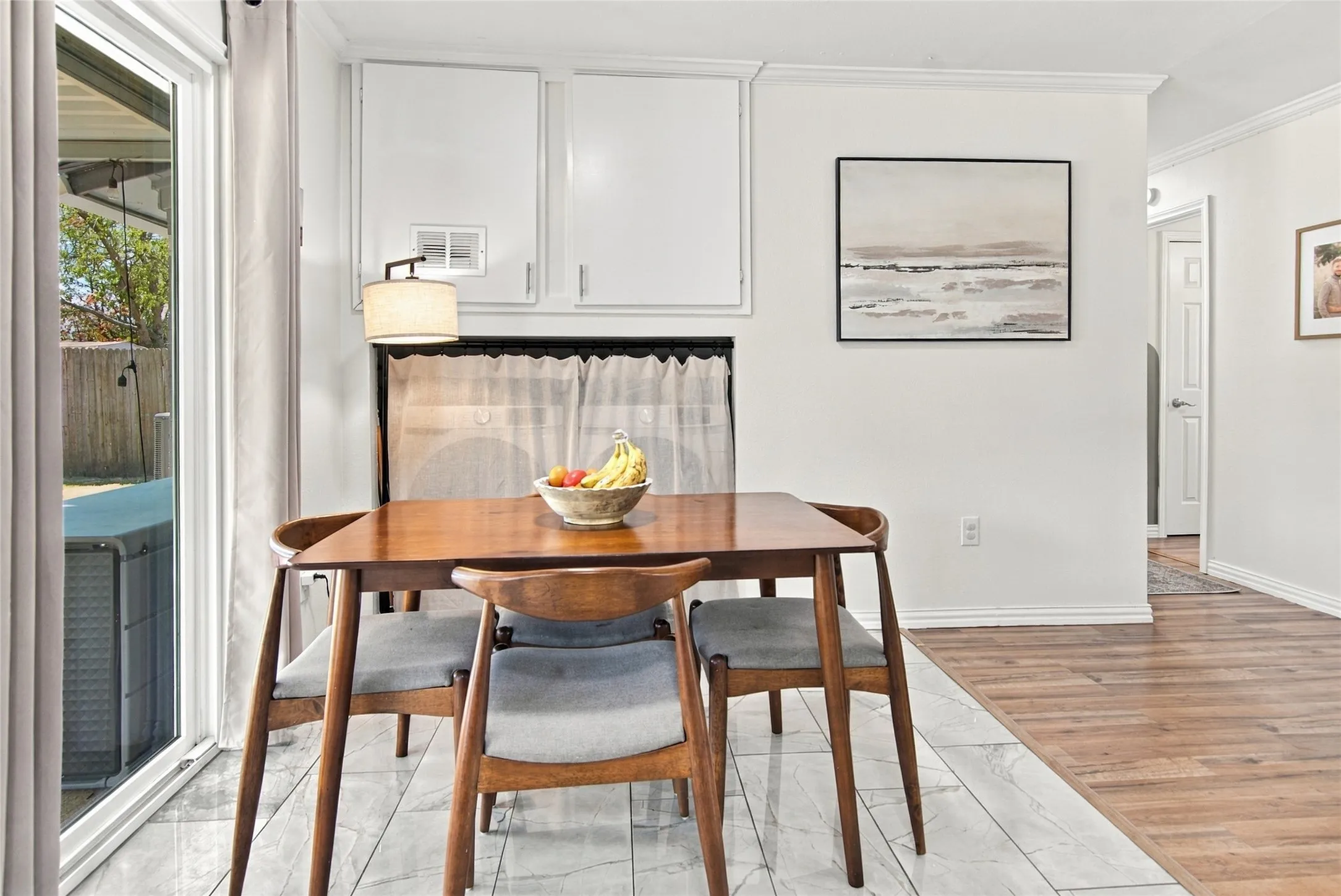 Sliding glass door, white wall cabinetry, crown molding, wood-finish flooring, and light-toned tile flooring