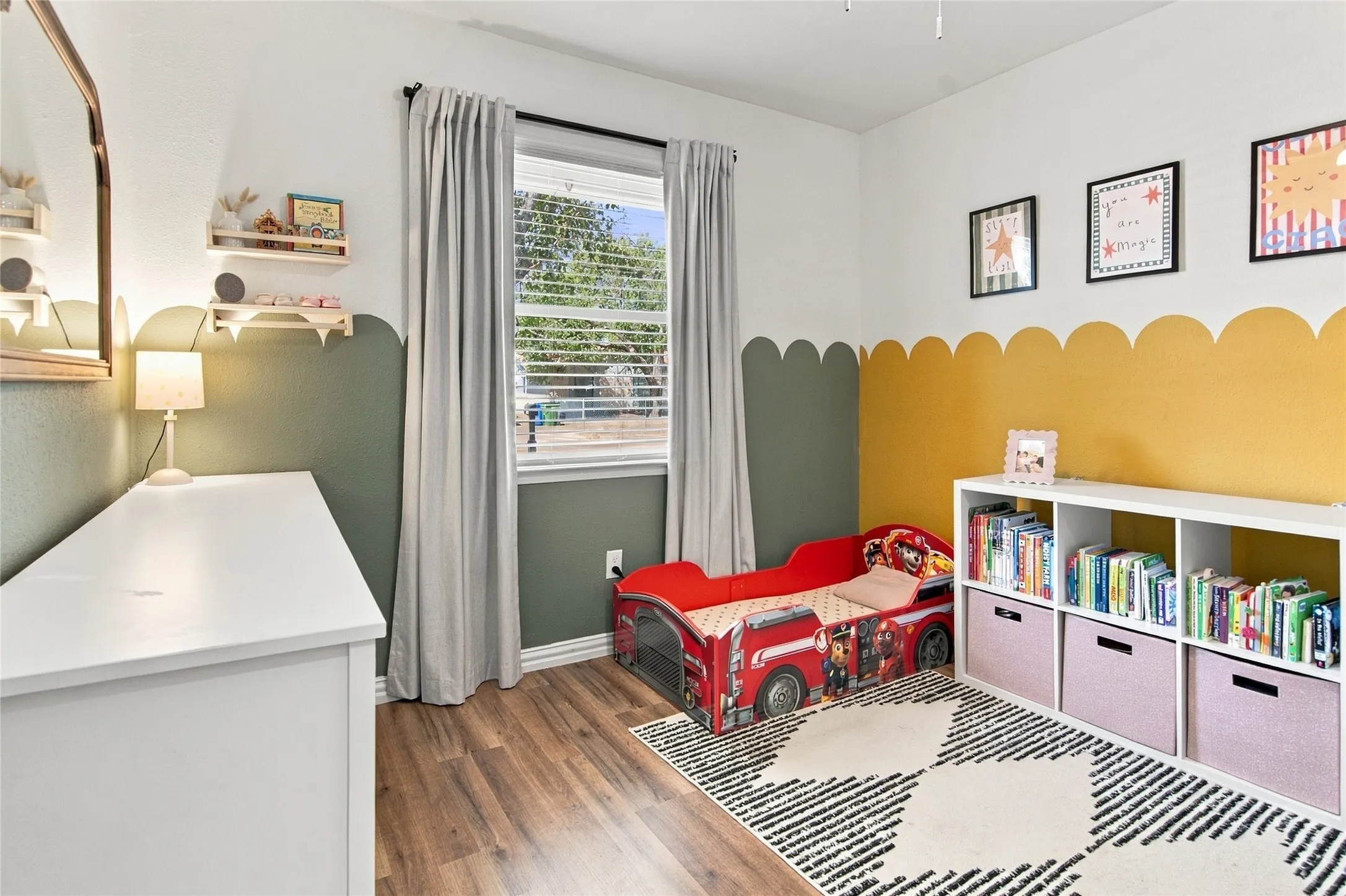 Wood-finish flooring, built-in shelving unit, natural light from a window, and decorative wall treatments