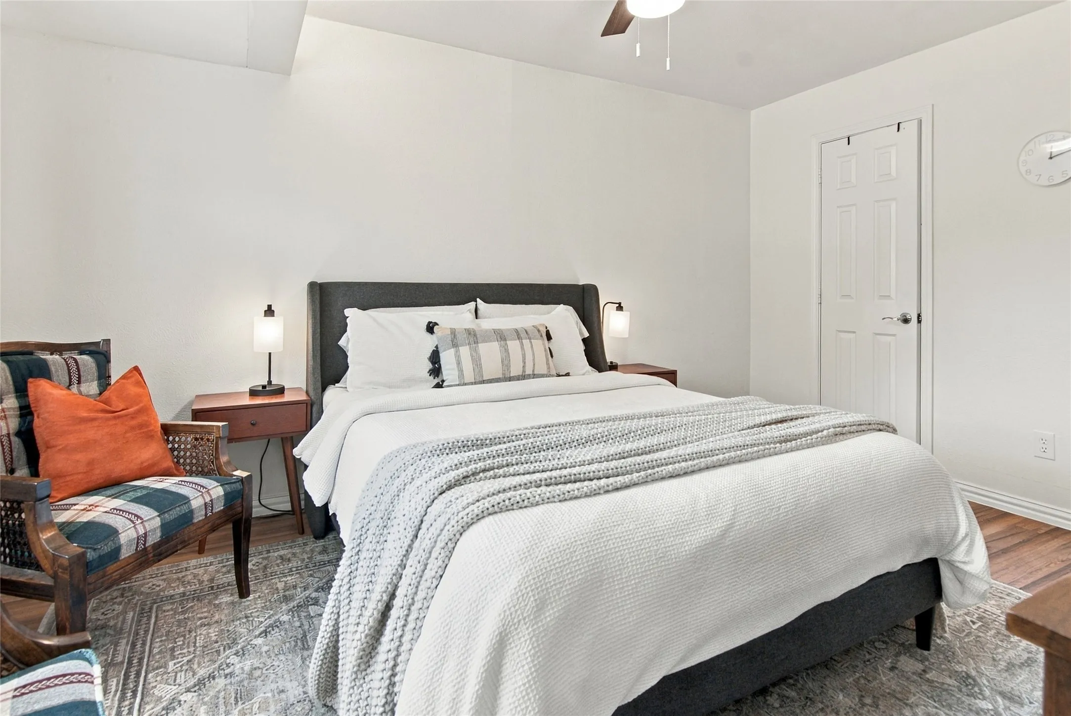 Wood-finish flooring, ceiling fan, white paneled door, and neutral wall tones