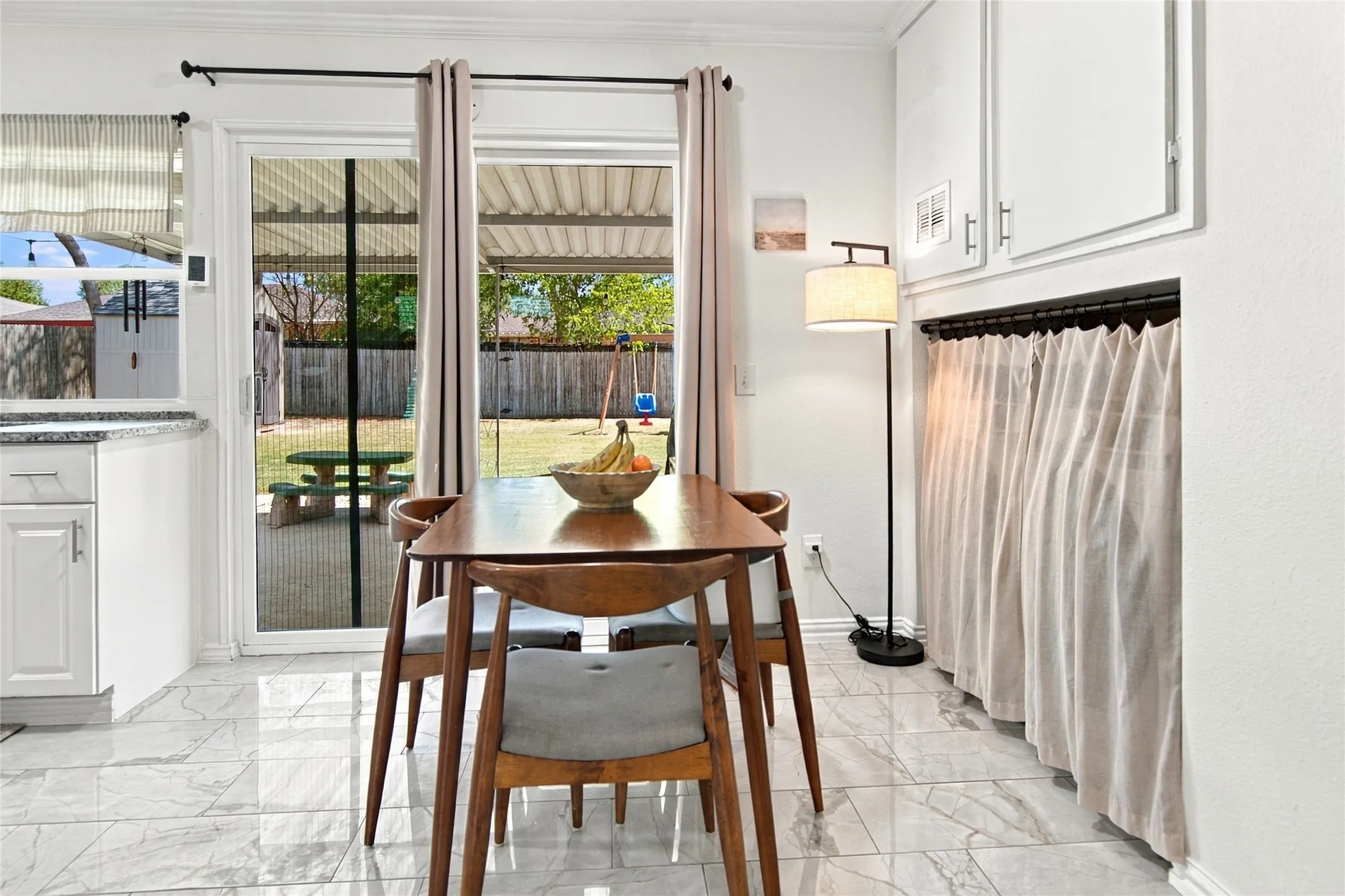 White shaker cabinetry, light-toned tile flooring, and a sliding glass door with screen leading to the exterior