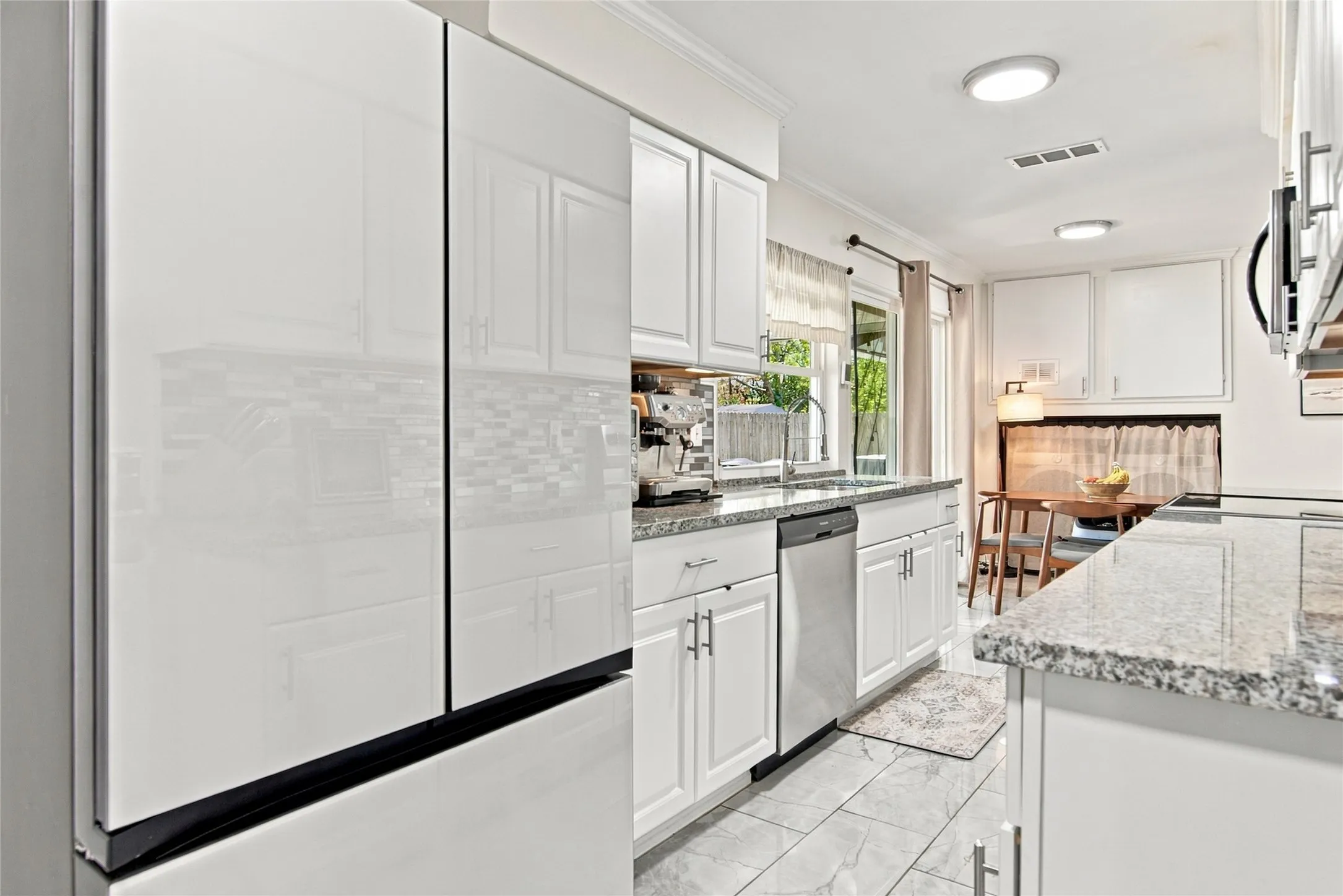 White cabinetry with brushed nickel hardware, light-toned granite-style countertops, mosaic tile backsplash, and recessed lighting