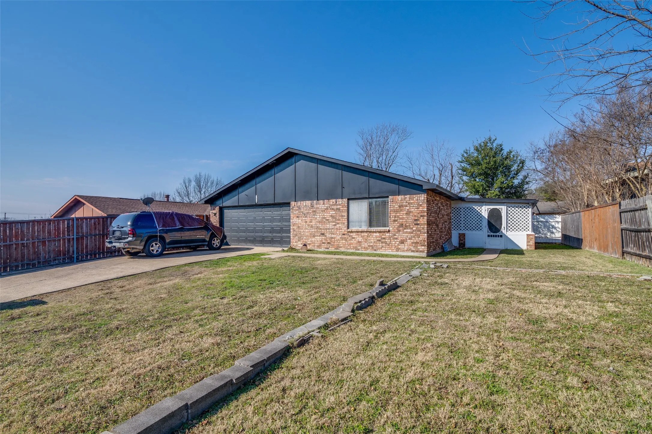 Brick exterior with a black garage door and an attached trellis feature