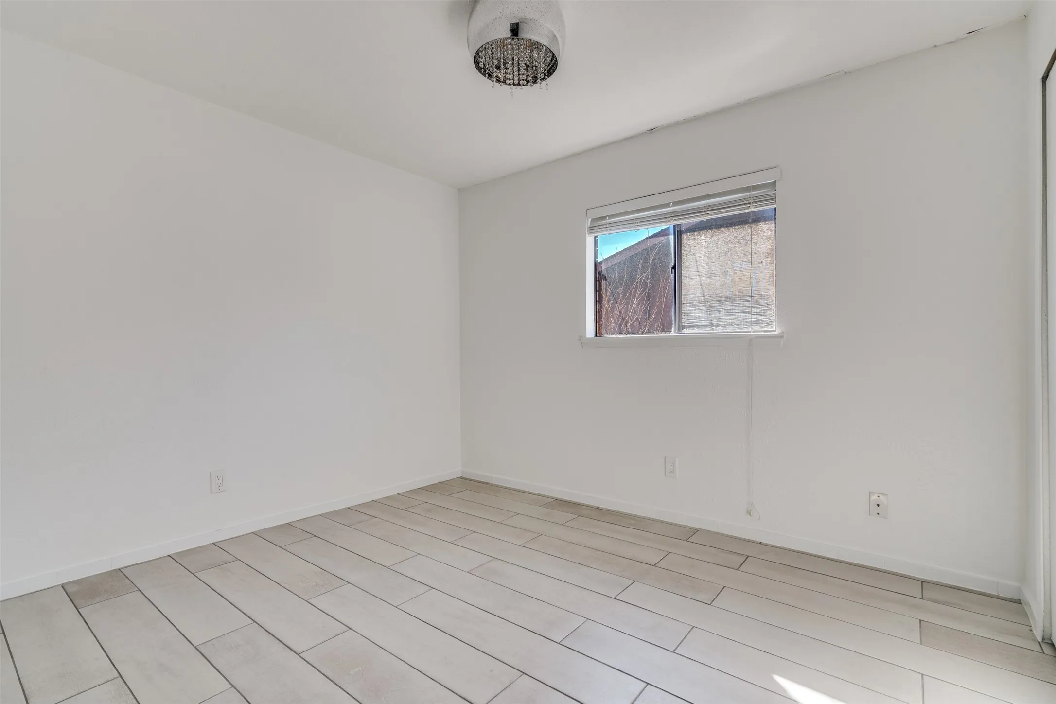 Recessed window with horizontal blinds, overhead flush-mount light fixture, and wood-look tile flooring