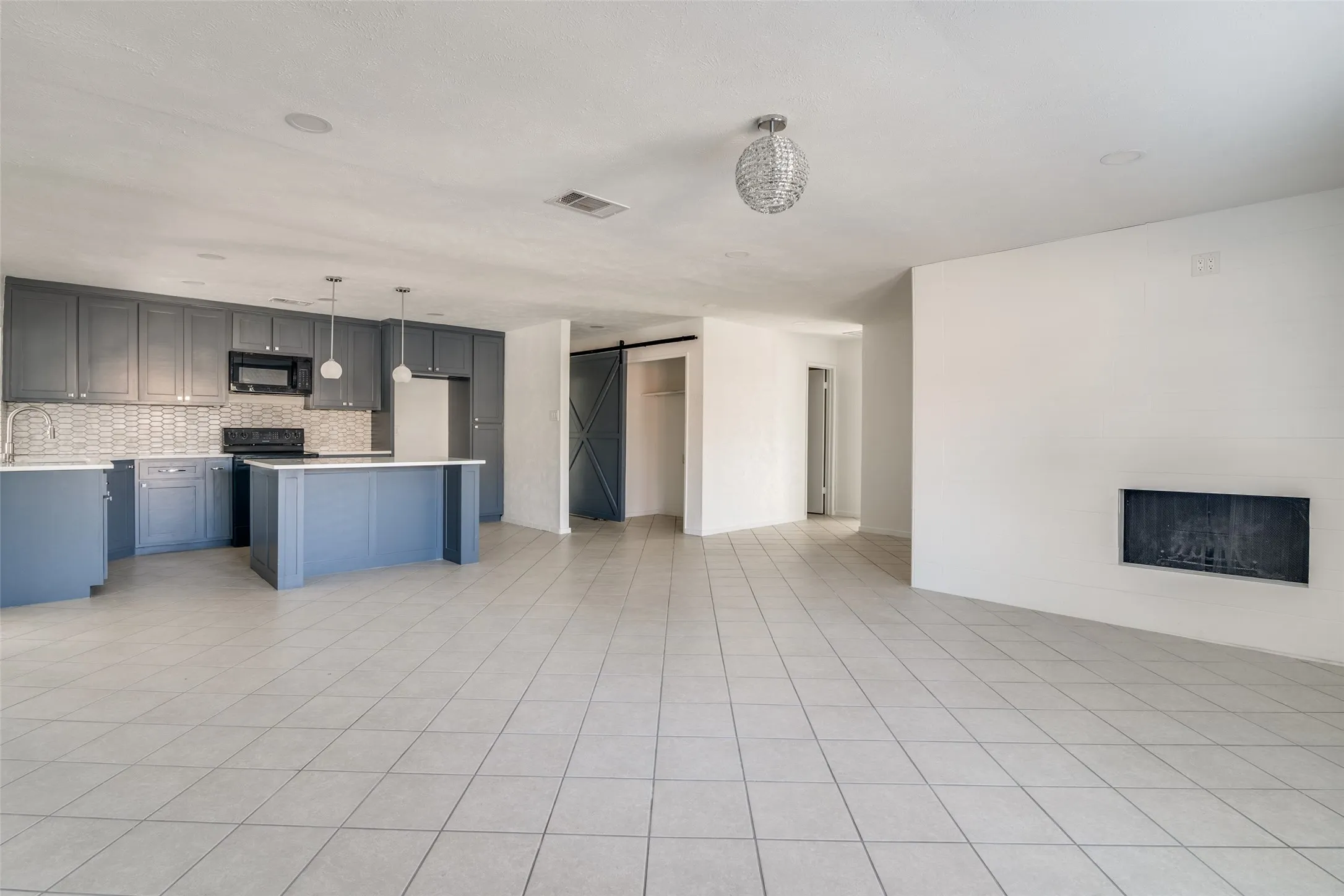 Kitchen featuring gray shaker cabinetry, a tile backsplash, an island, and pendant lighting