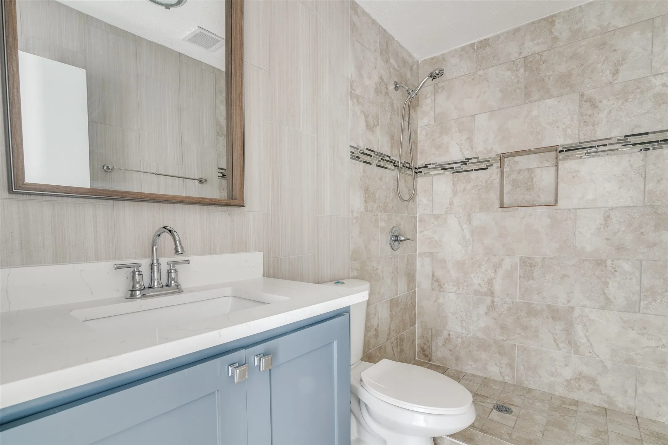 Vanity with a white countertop and undermount sink, chrome faucet, and blue cabinetry with chrome pulls