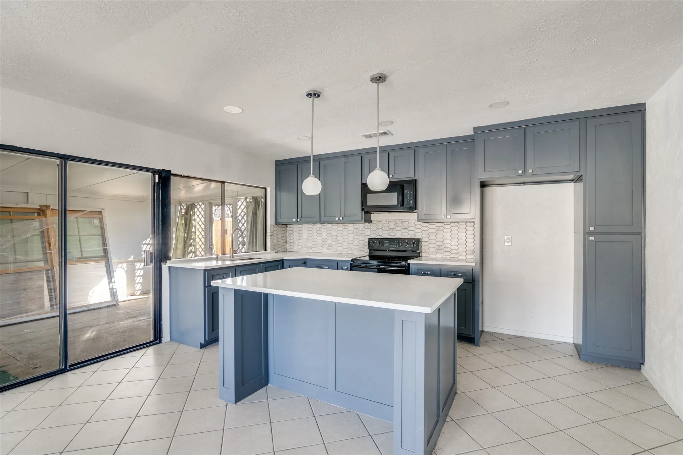 Kitchen featuring gray cabinetry, white countertops, tile flooring, and a patterned tile backsplash