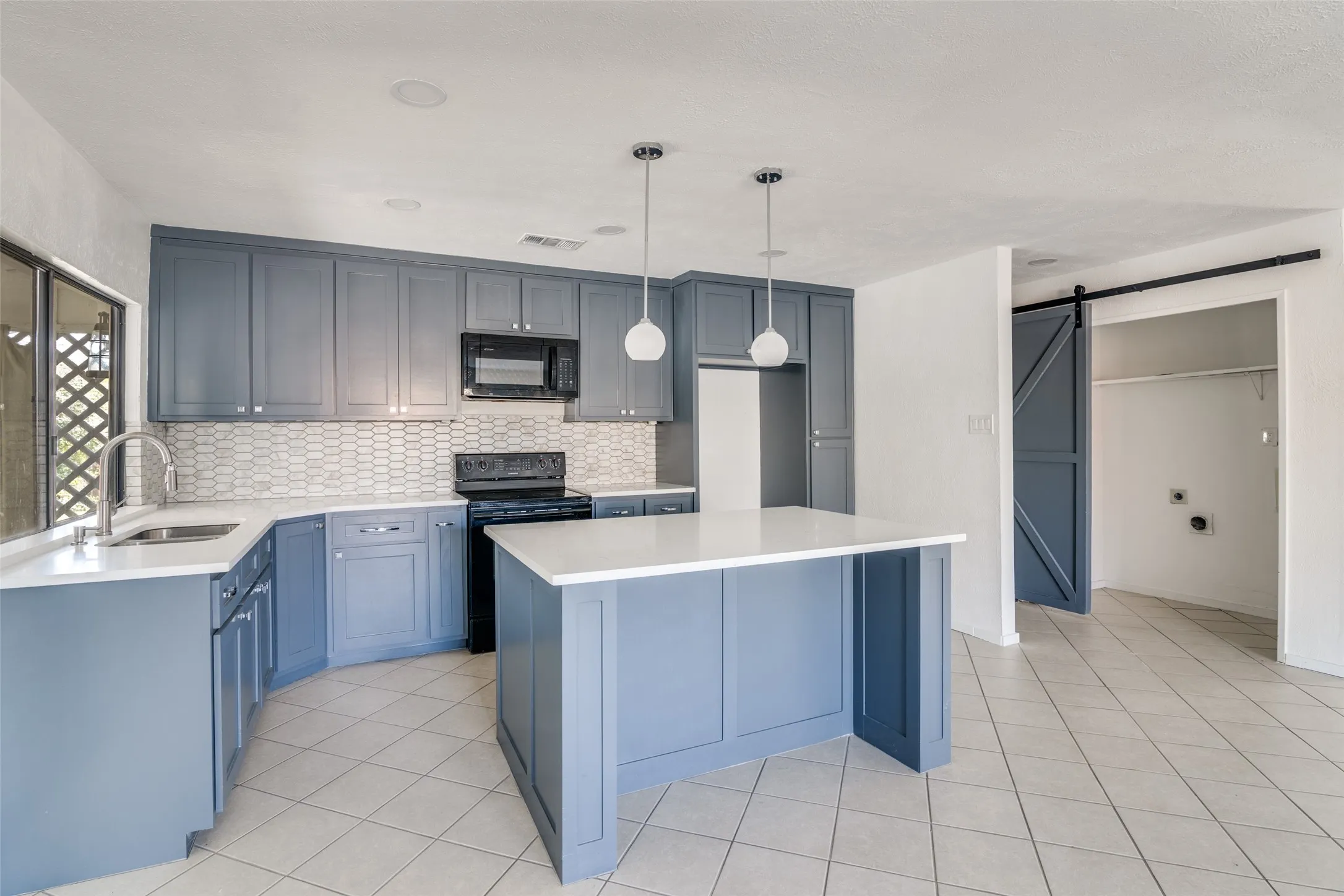 Updated kitchen featuring blue shaker cabinetry, white countertops, tile backsplash, and a central island with pendant lighting