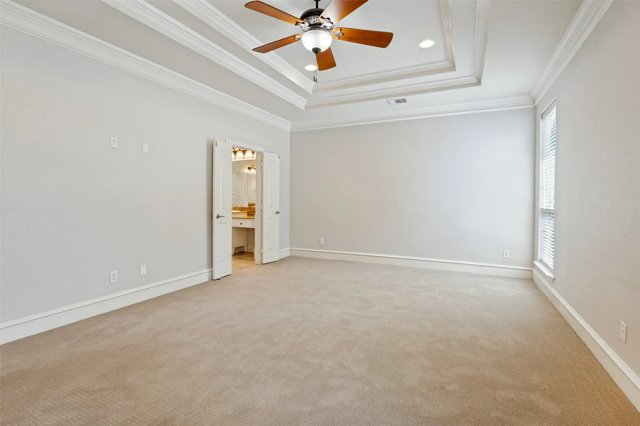 Spacious room featuring tray ceiling with a ceiling fan, recessed lighting, carpeted flooring, and a window with blinds