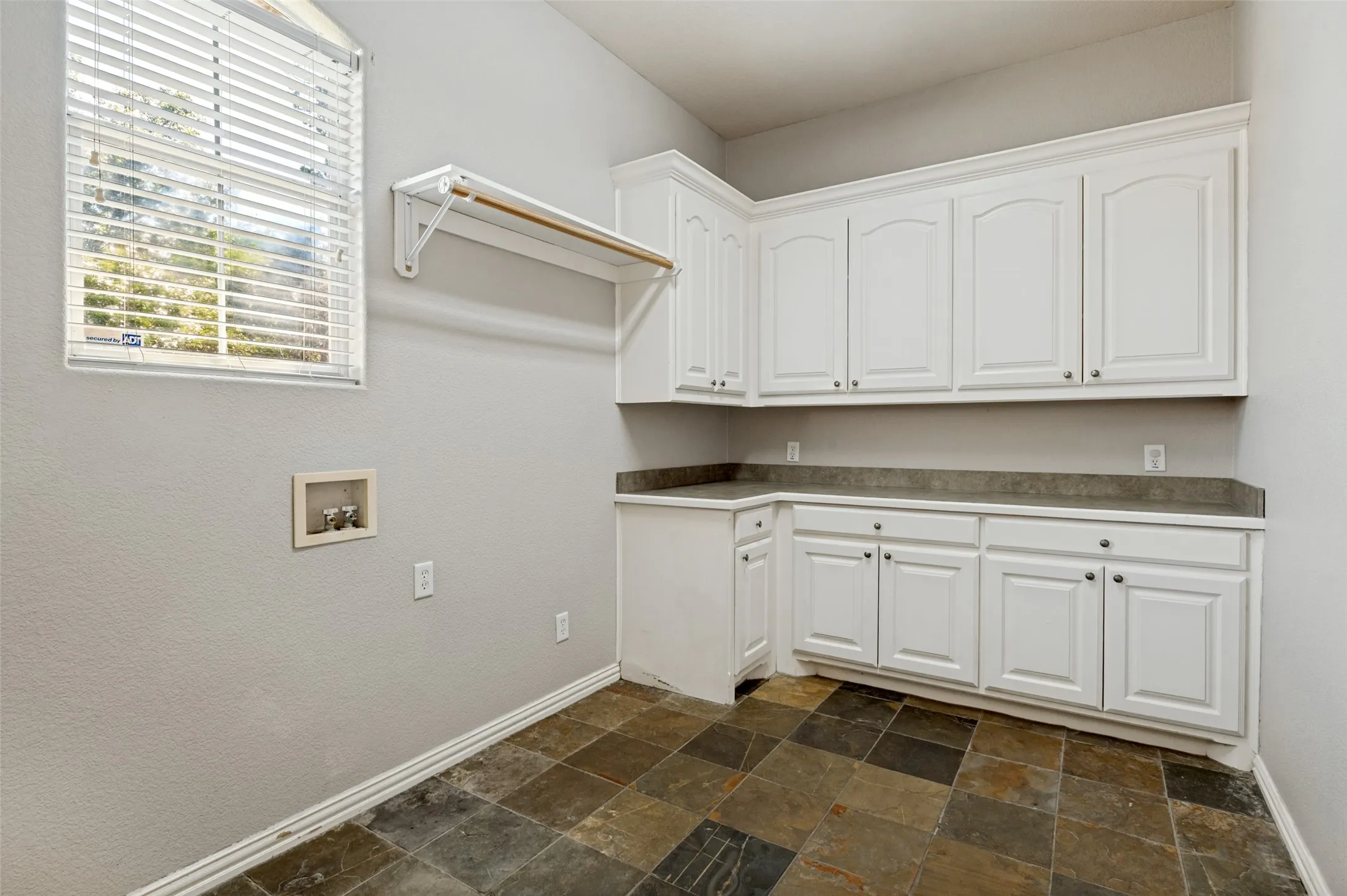 Slate-style floor tile, white shaker-style cabinetry, and dark-toned countertops