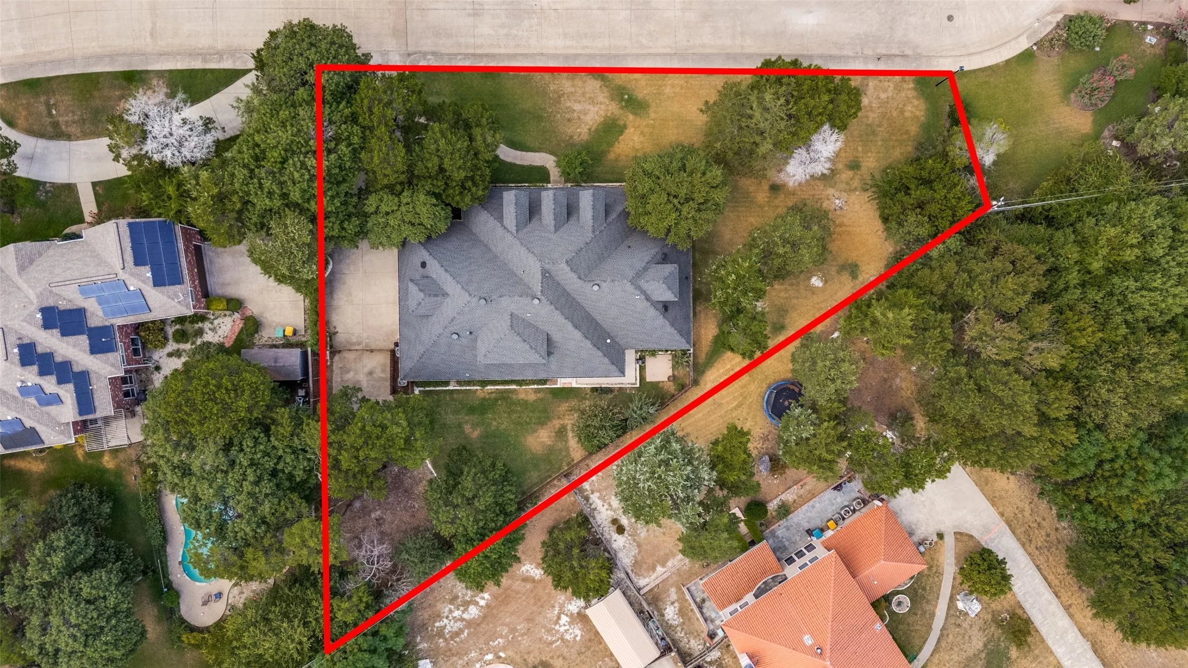 Property with mature tree coverage, a multi-gabled roofline, and a paved driveway