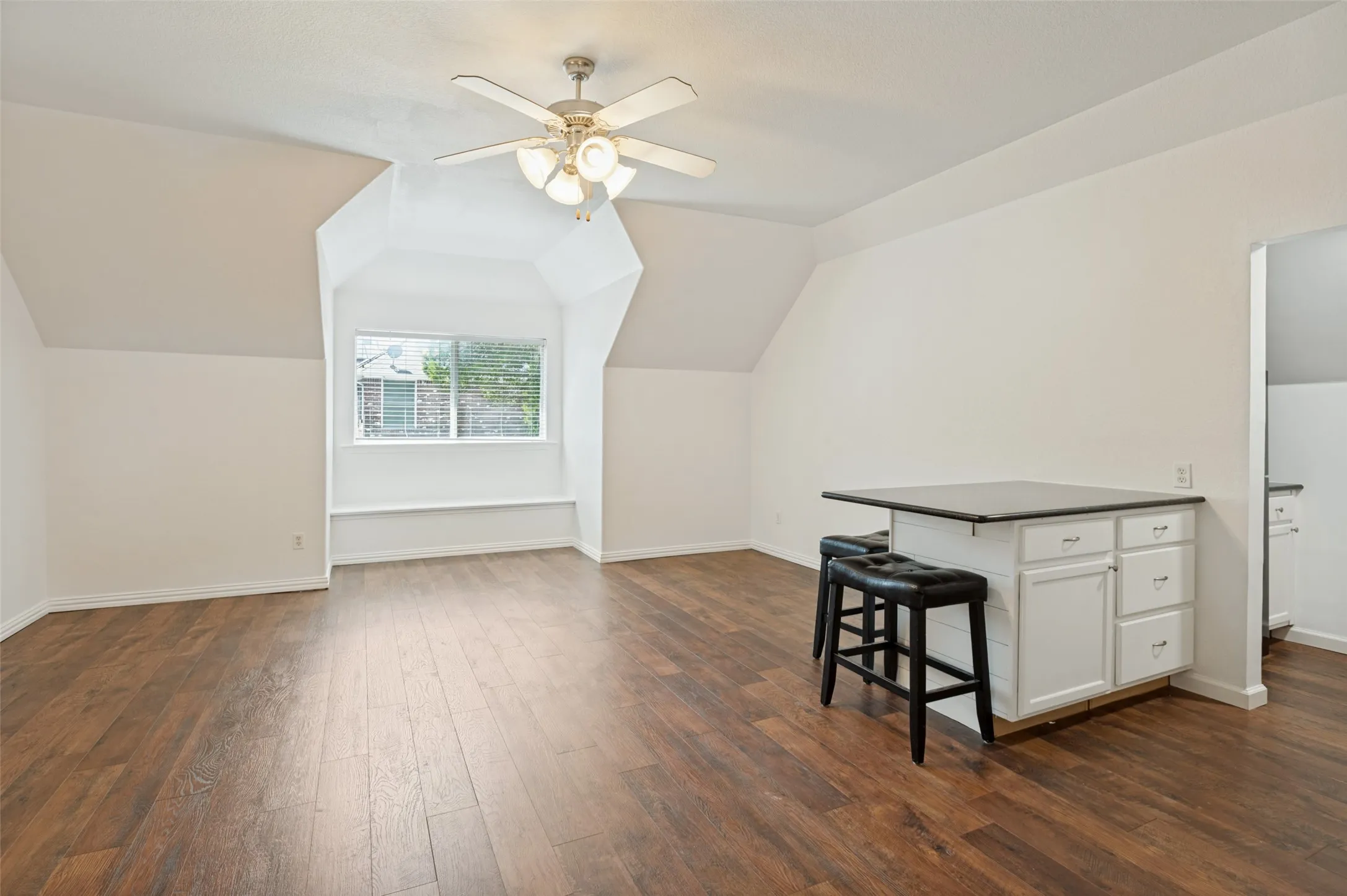 Wood-finish flooring, built-in window seating, recessed window, white cabinetry, and ceiling fan with integrated lighting