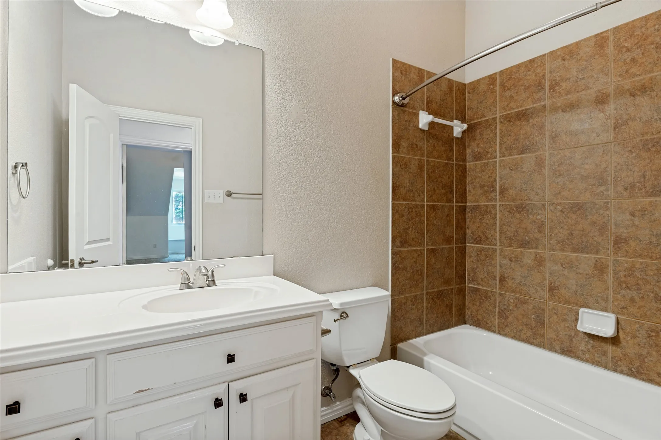 White vanity with integrated sink, brushed nickel faucet, large mirror, and overhead vanity lighting