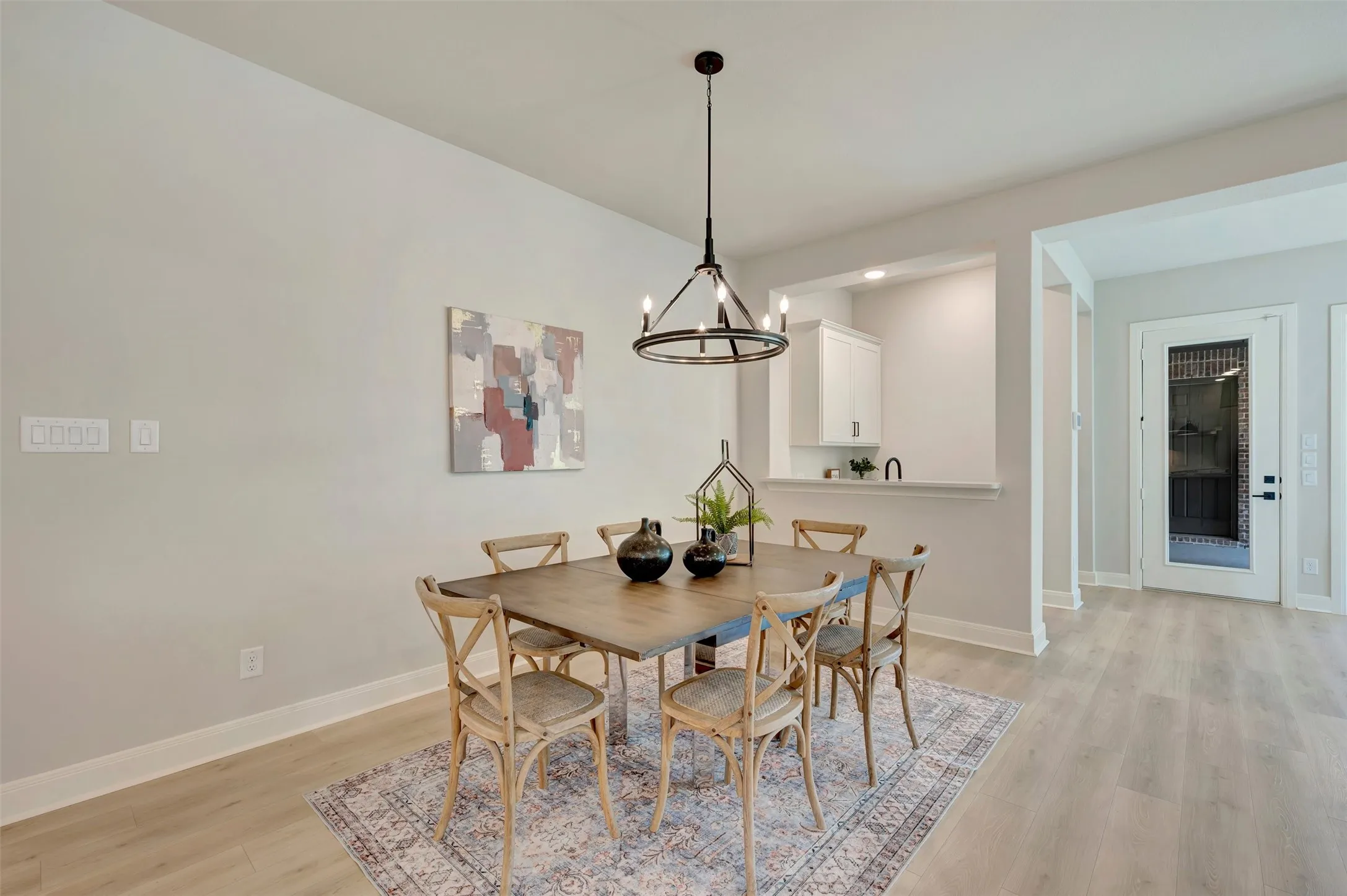 Light wood-finish flooring throughout, with a contemporary dark-finish chandelier and recessed lighting