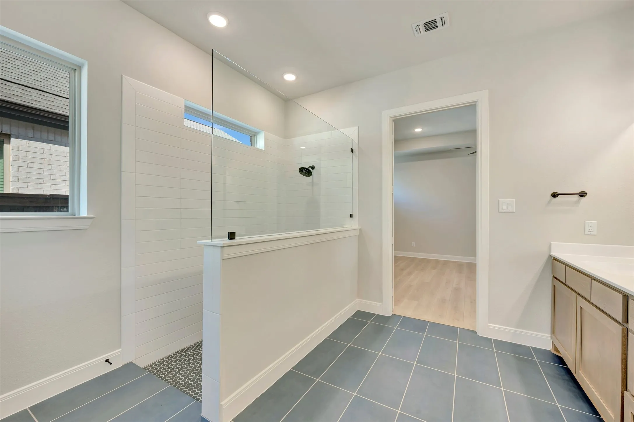Walk-in shower with full glass enclosure, white subway tile surround, recessed lighting, and a transom window