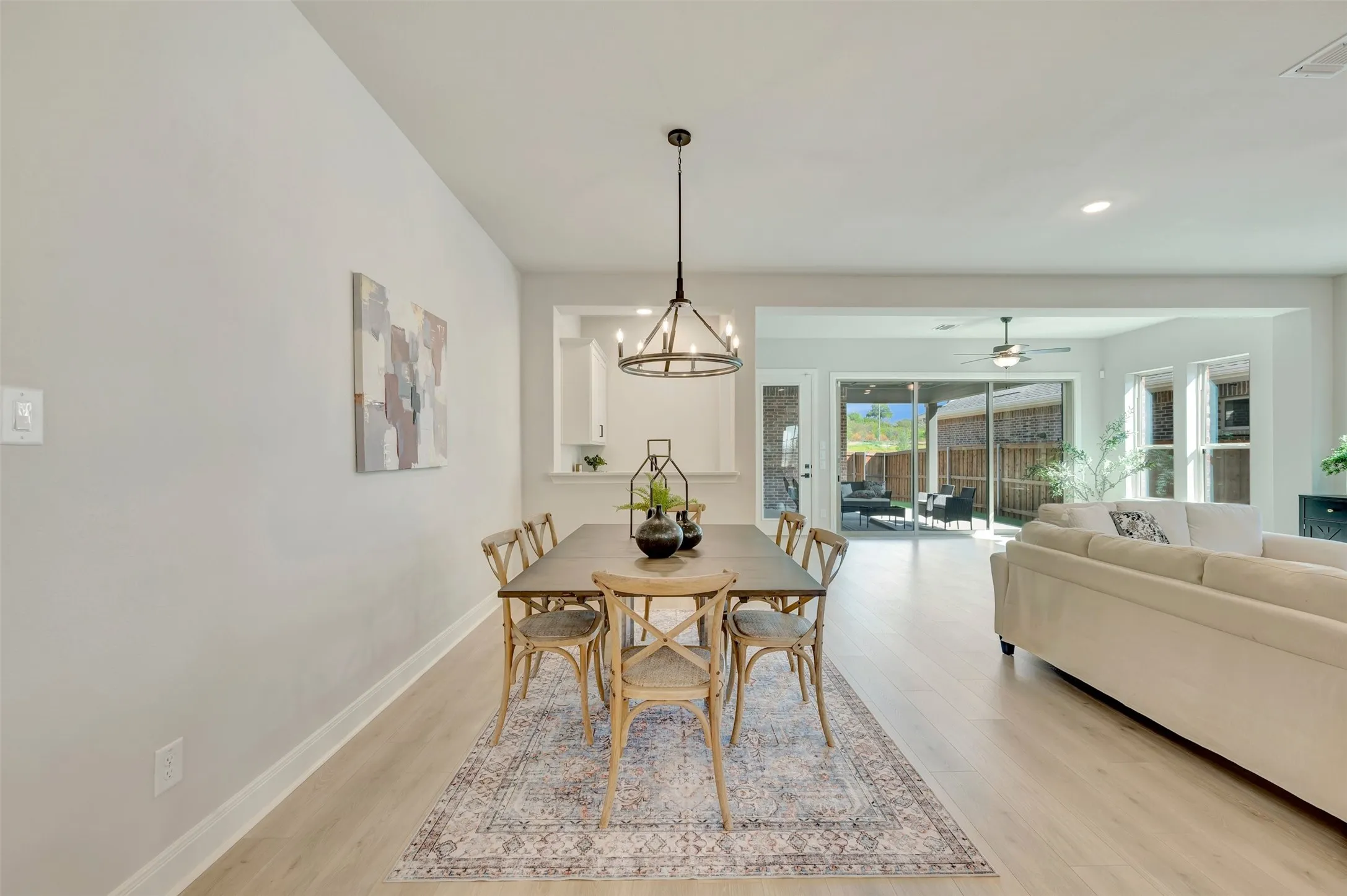 Open-concept layout featuring light wood-finish flooring, a contemporary chandelier, and a wall cut-out to a built-in cabinet
