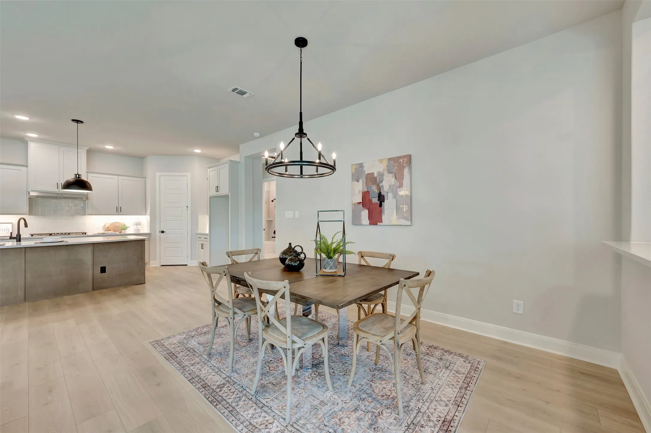 Open-concept design featuring wood-finish flooring, a kitchen with light-toned cabinetry, and an island with a contrasting finish
