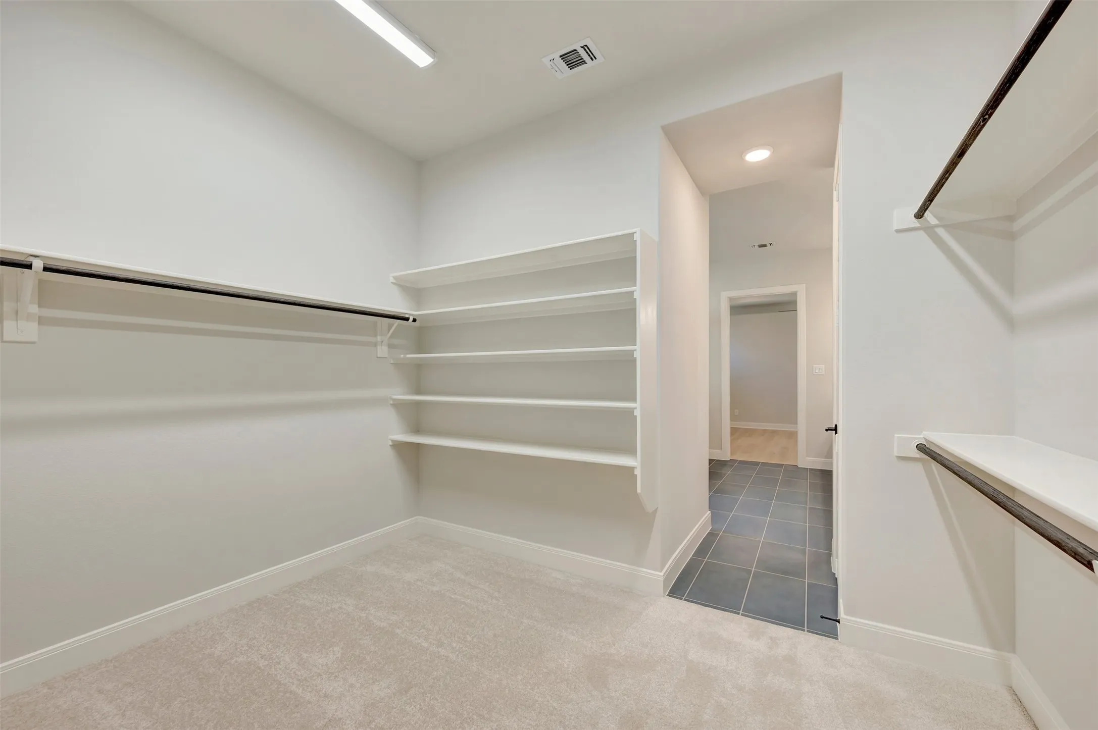 Built-in shelving, hanging rods, carpet flooring, recessed lighting, and tile flooring